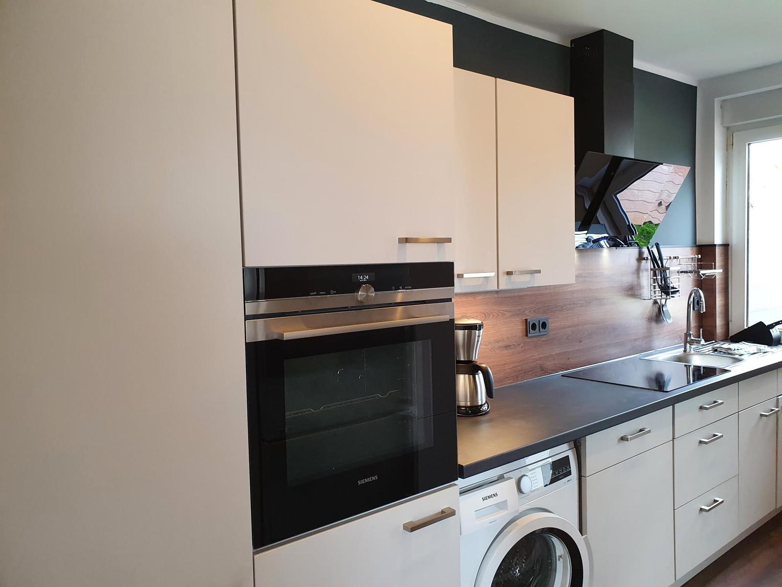 Moderne Küche mit integriertem Backofen und Spülmaschine.