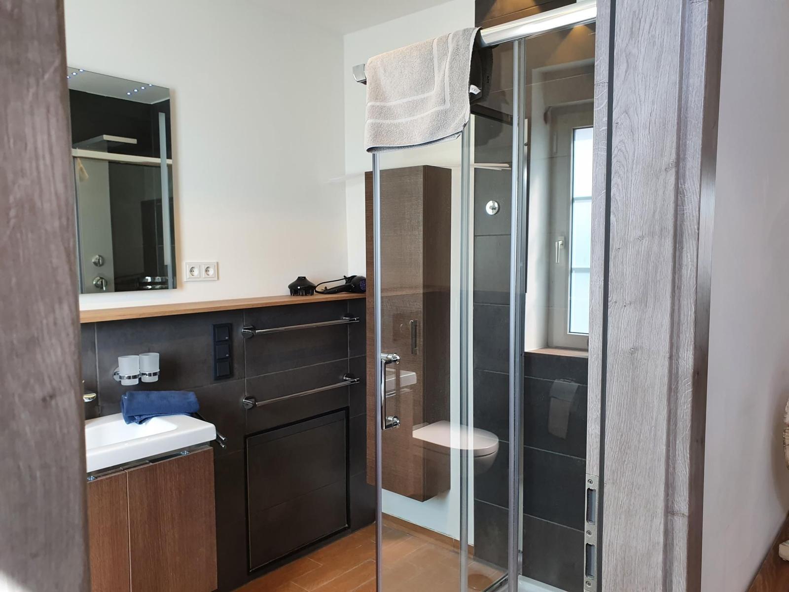 Badezimmer mit Dusche, Waschbecken und Spiegel