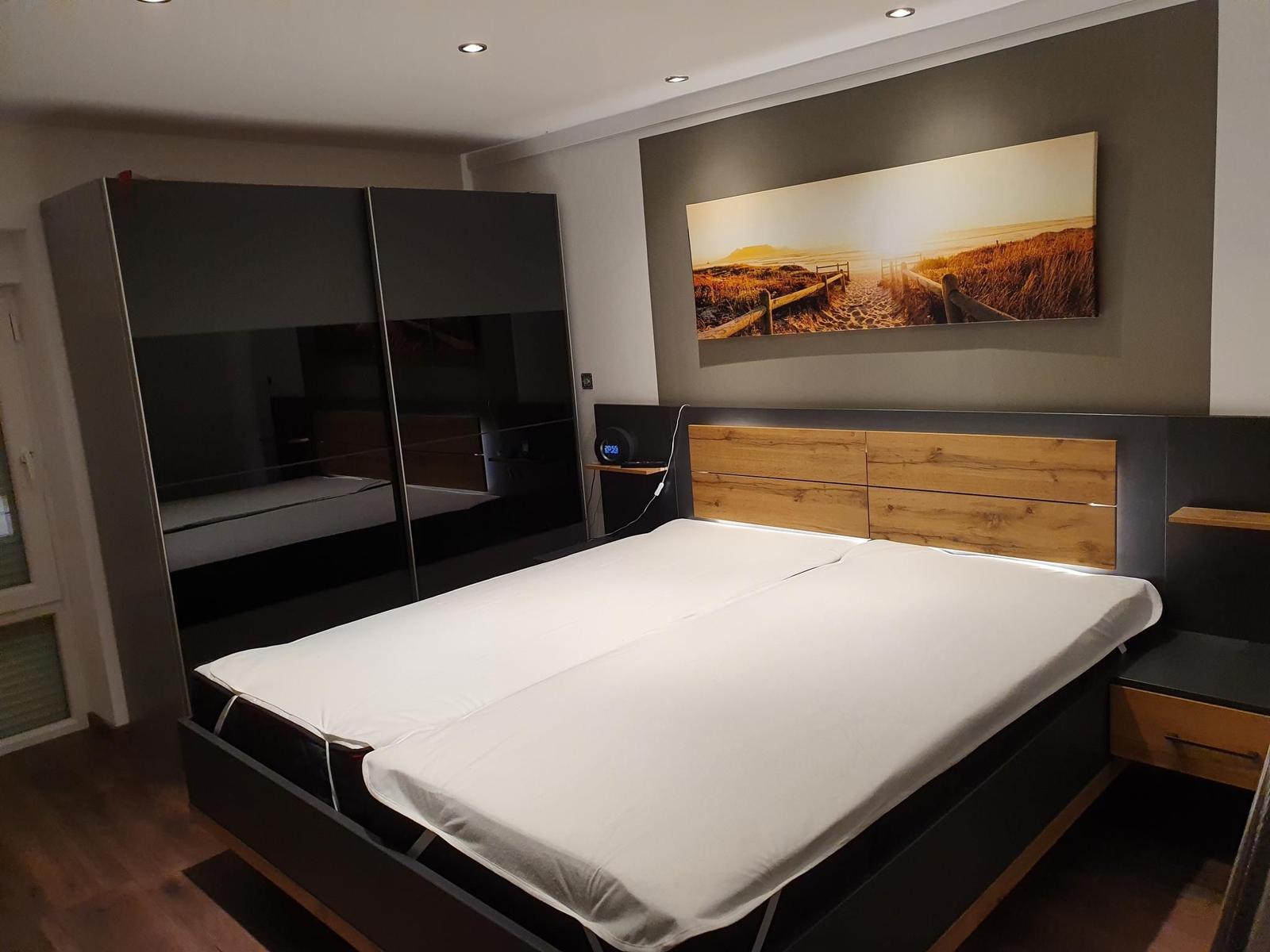 Schlafzimmer mit Doppelbett, Kleiderschrank und Wandbild.