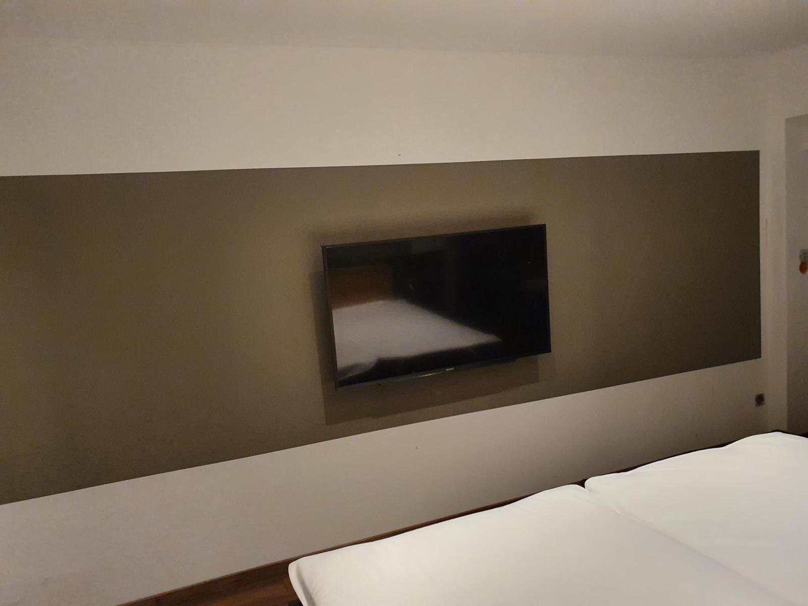 Schlafzimmer mit Bett und Wandfernseher