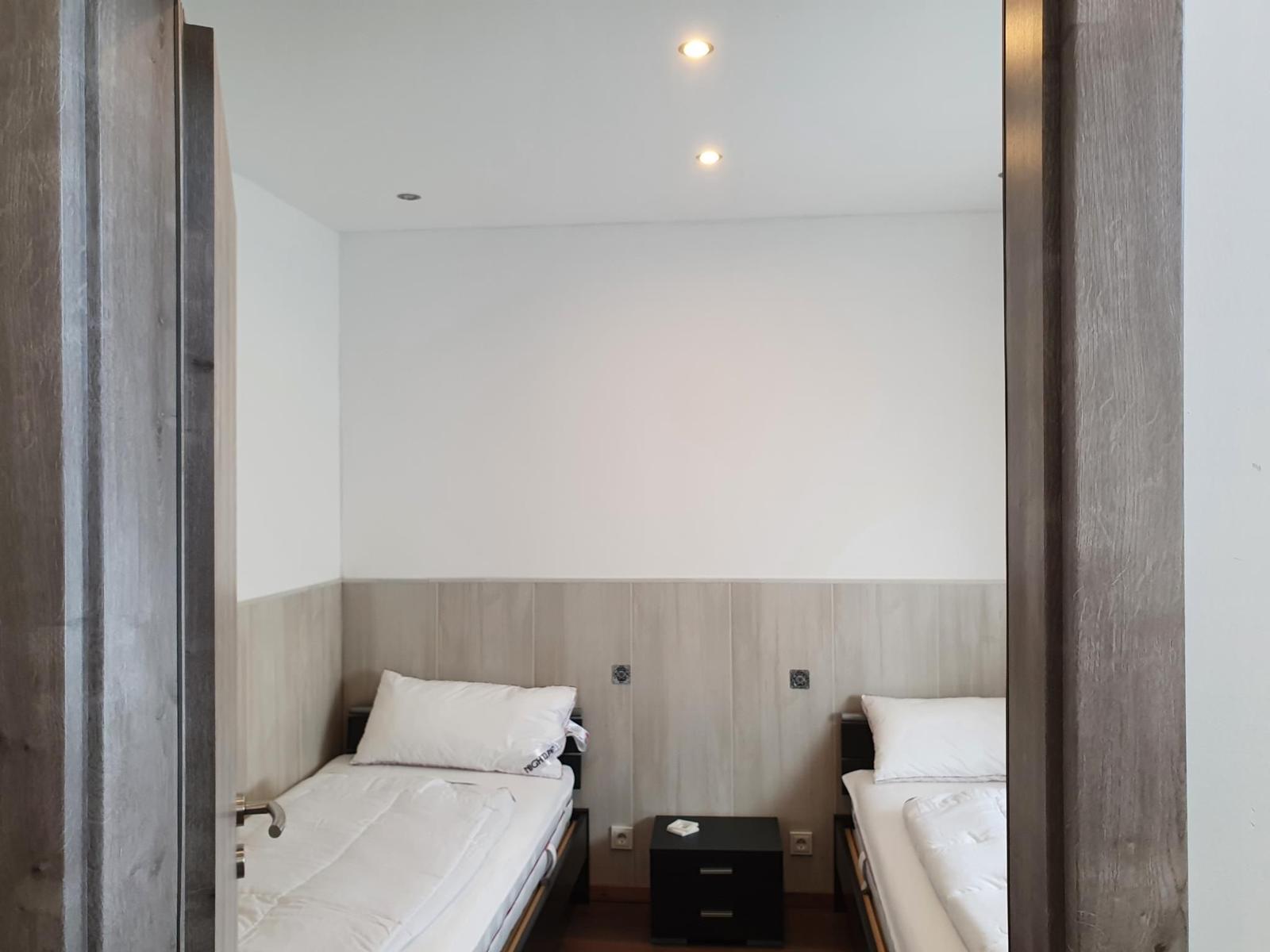 Zwei Einzelbetten mit weißer Bettwäsche und einem Nachttisch dazwischen.