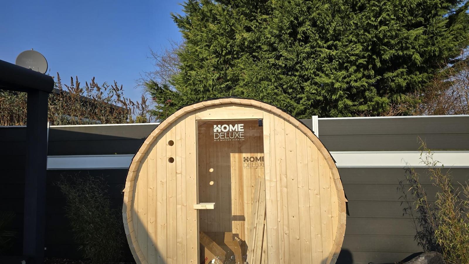 Holzsauna im Garten mit Sichtfenster und Logo