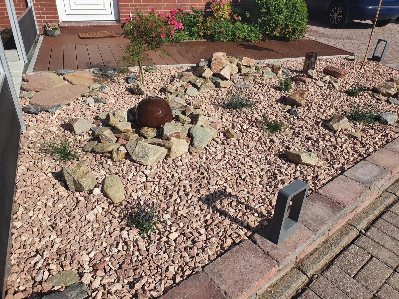 Garten mit Kies, Steinen und Pflanzen vor der Haustür.