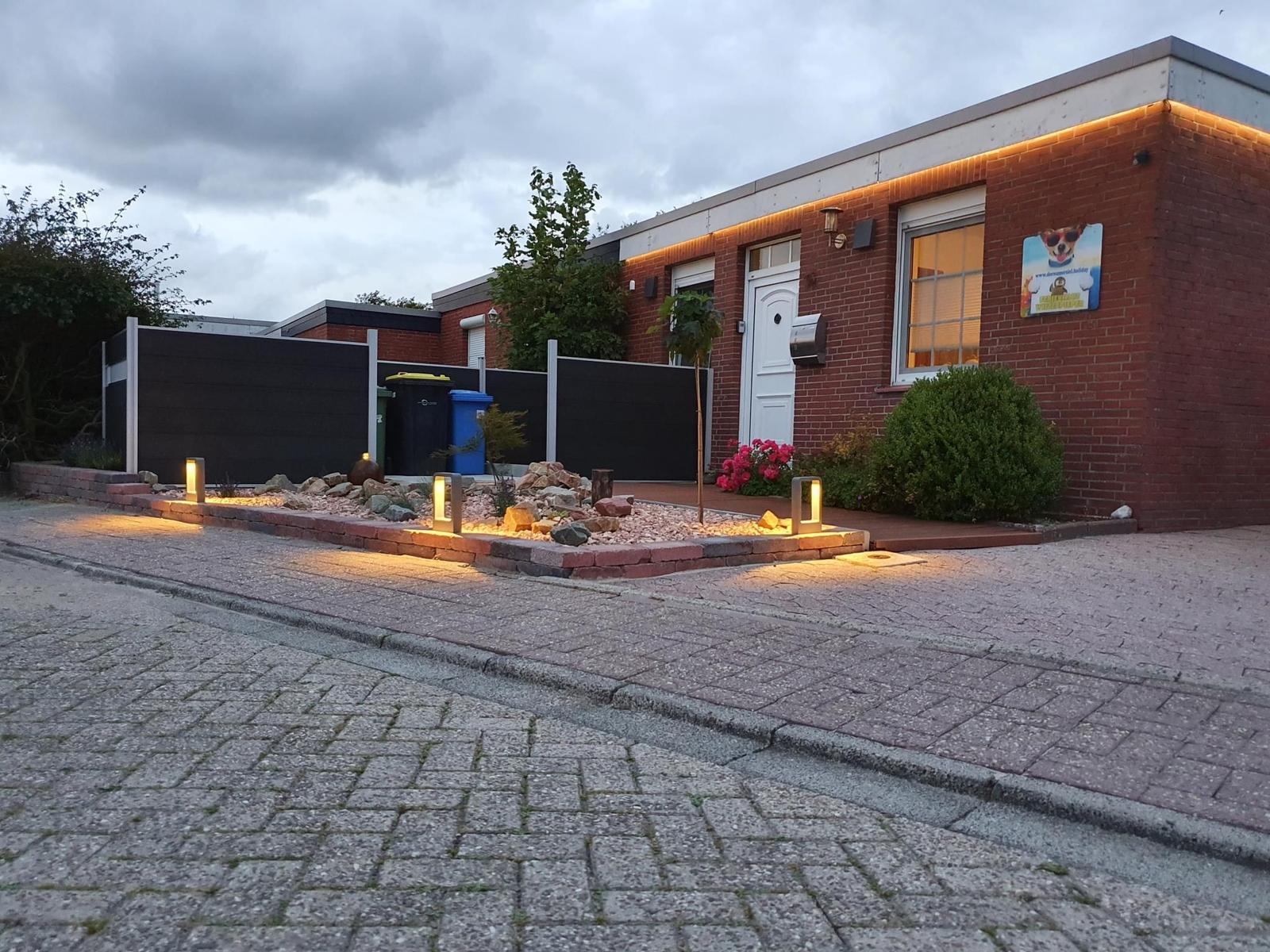 Rotes Backsteinhaus mit beleuchteter Fassade und gepflastertem Vorplatz.