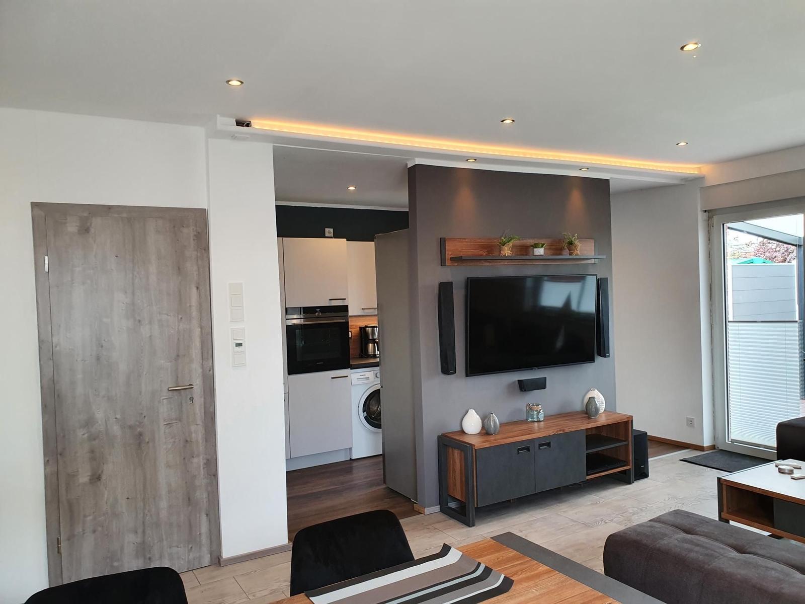 Wohnzimmer mit TV, Küchenbereich und Haustür