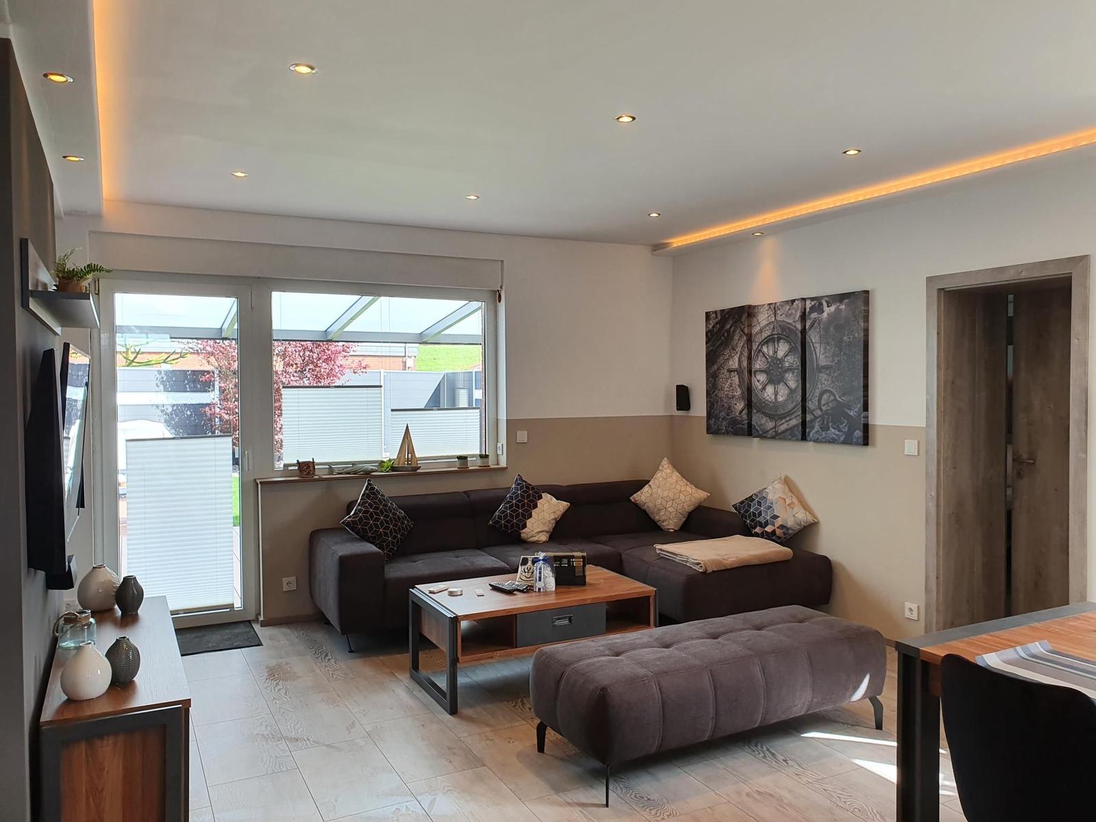 Wohnzimmer mit Sofa, Couchtisch und Fenster zur Terrasse.