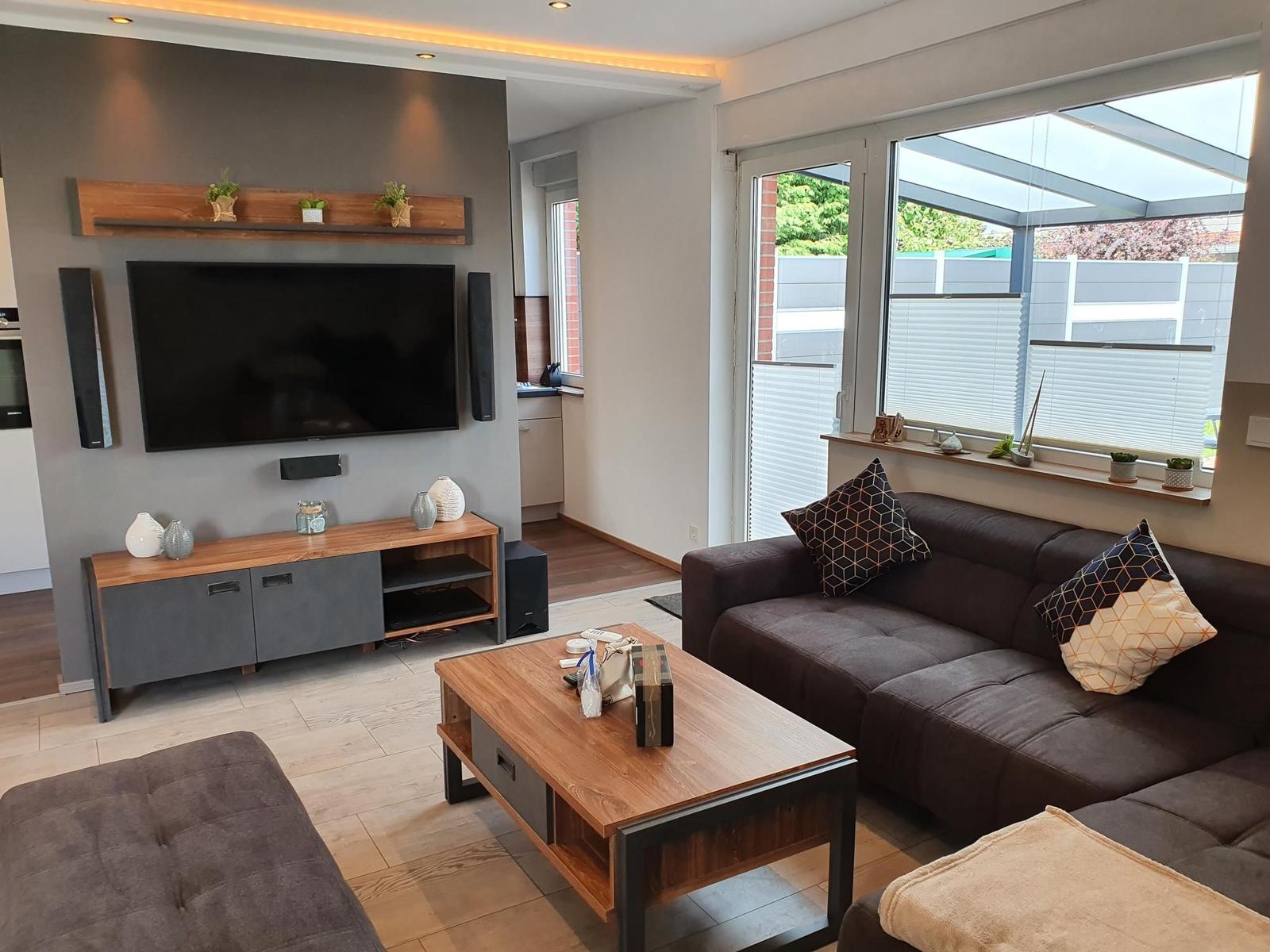 Wohnzimmer mit Sofa, Couchtisch und Fernseher an der Wand.