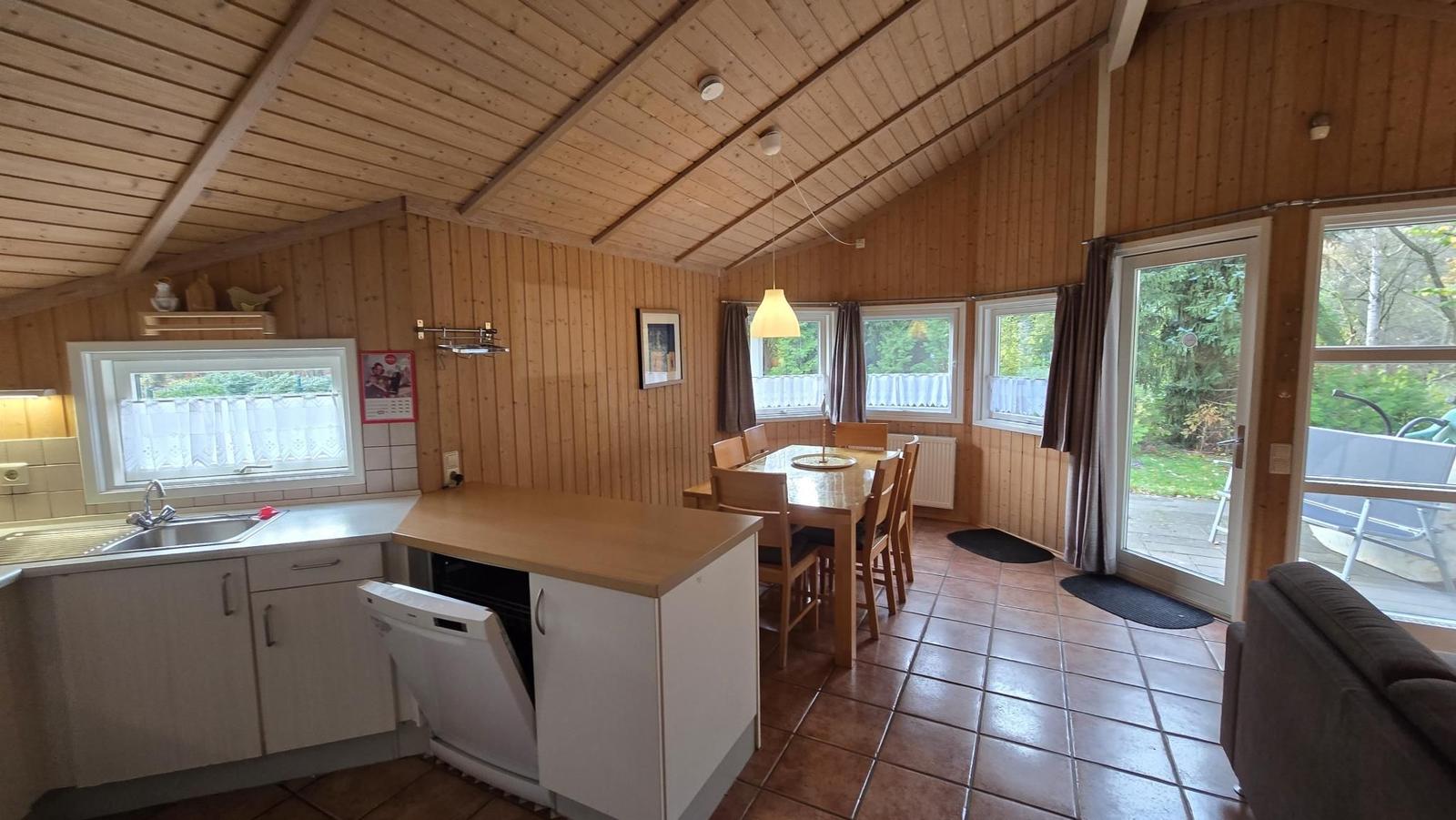 Küche mit Essbereich und Terrassenzugang. Holzwände und -decke.