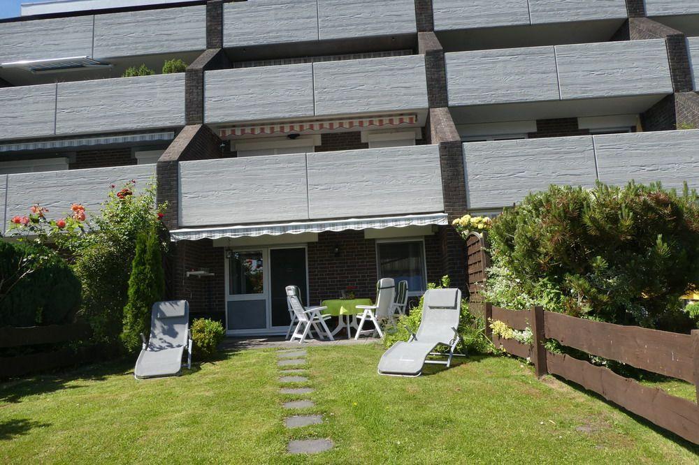 Garten mit Liegestühlen und Terrasse vor Mehrfamilienhaus