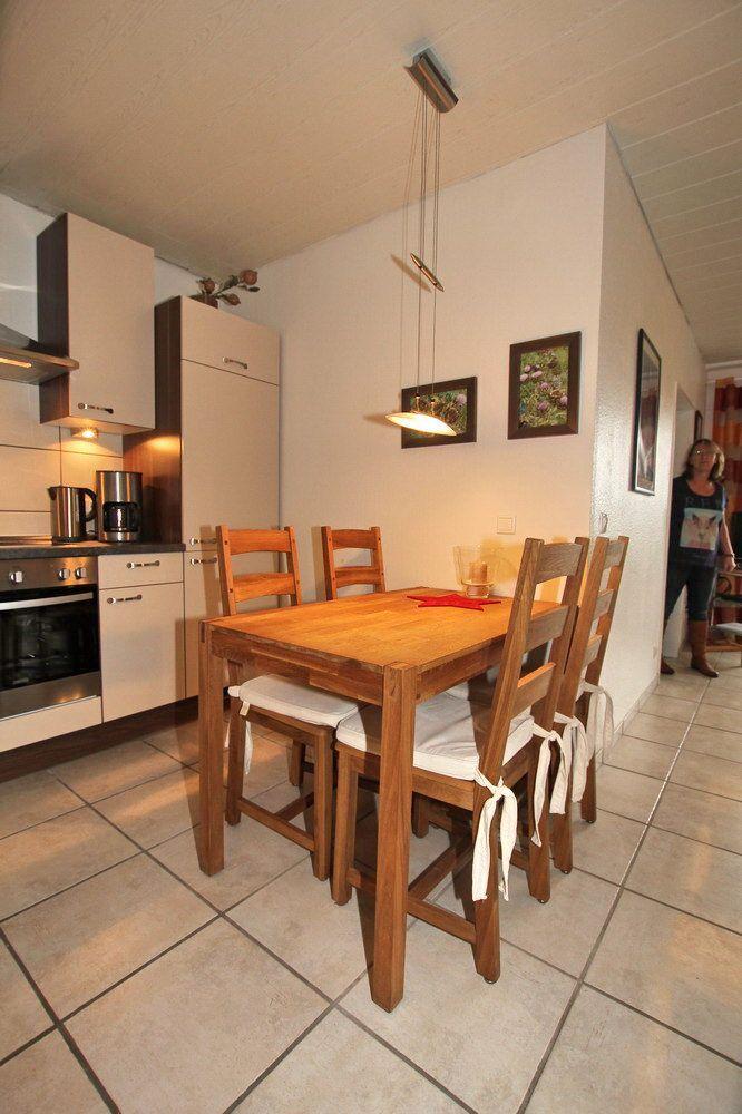 Küche mit Essbereich, Holztisch und -stühle, Wandbilder und Pendelleuchte.