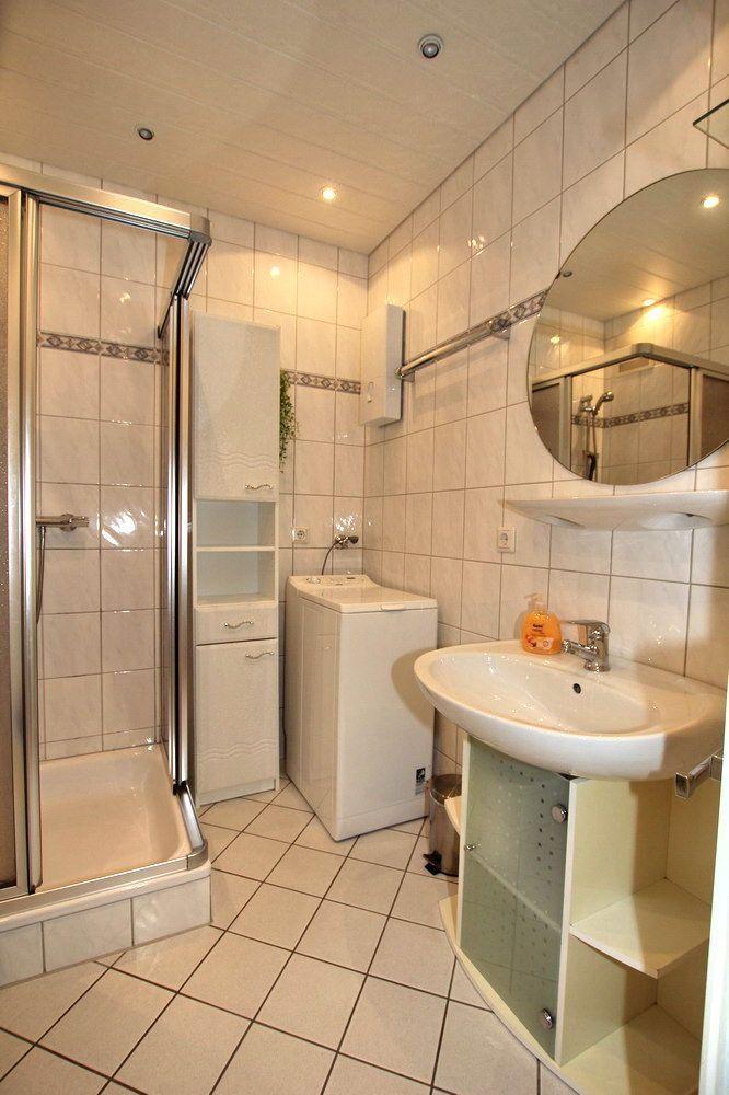 Badezimmer mit Dusche, Waschmaschine und Waschbecken