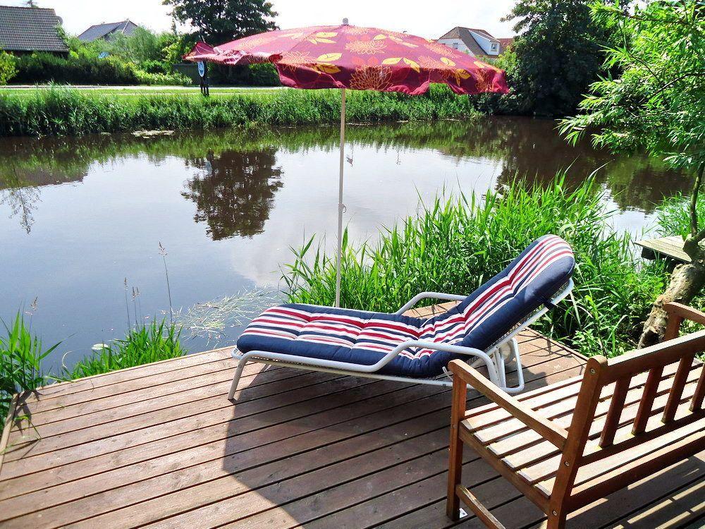 Terrasse mit Liegestuhl und Sonnenschirm am Wasser