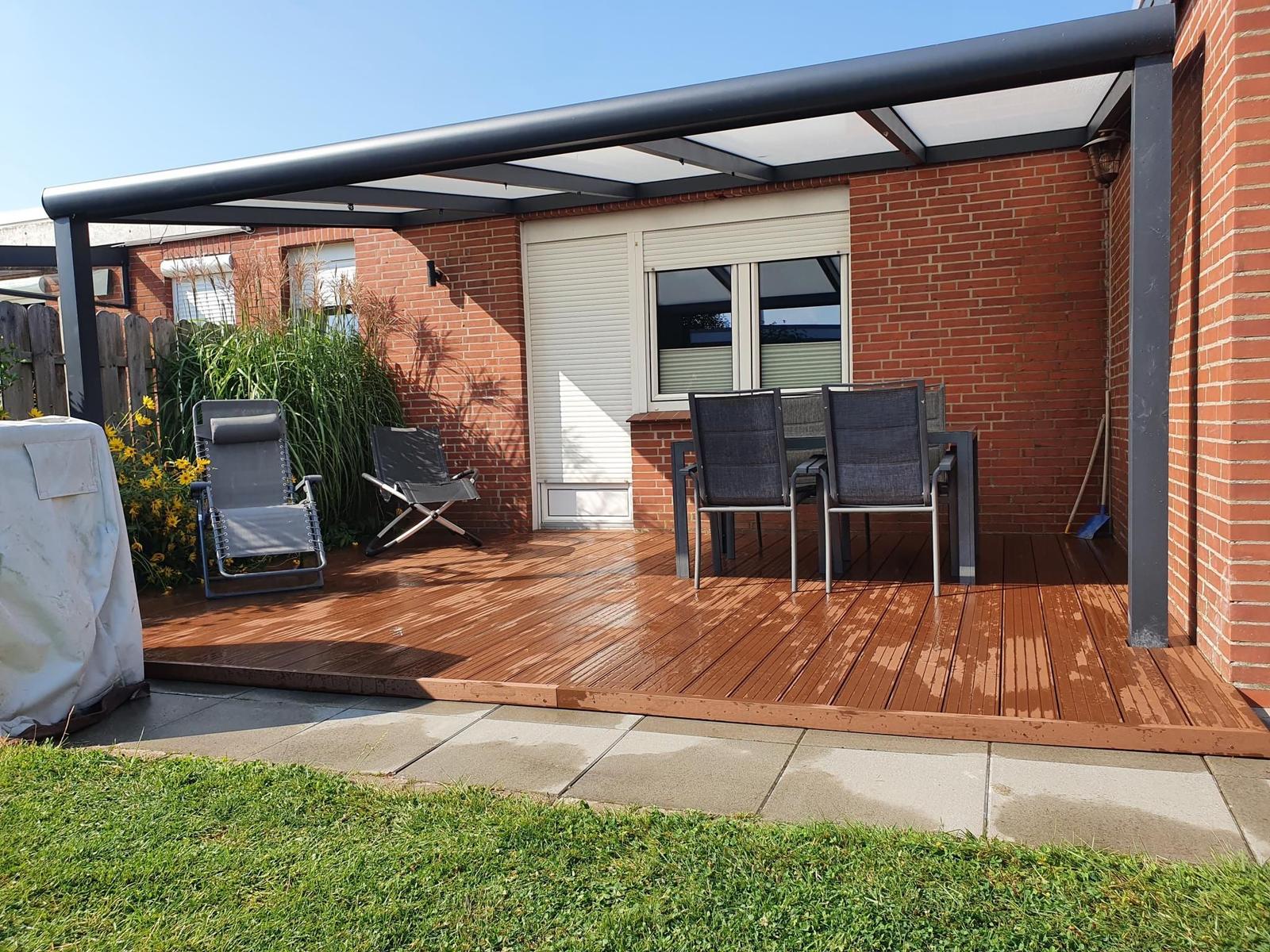 Terrasse mit Sitzgruppe, Sonnenschutz und Gartenbereich.