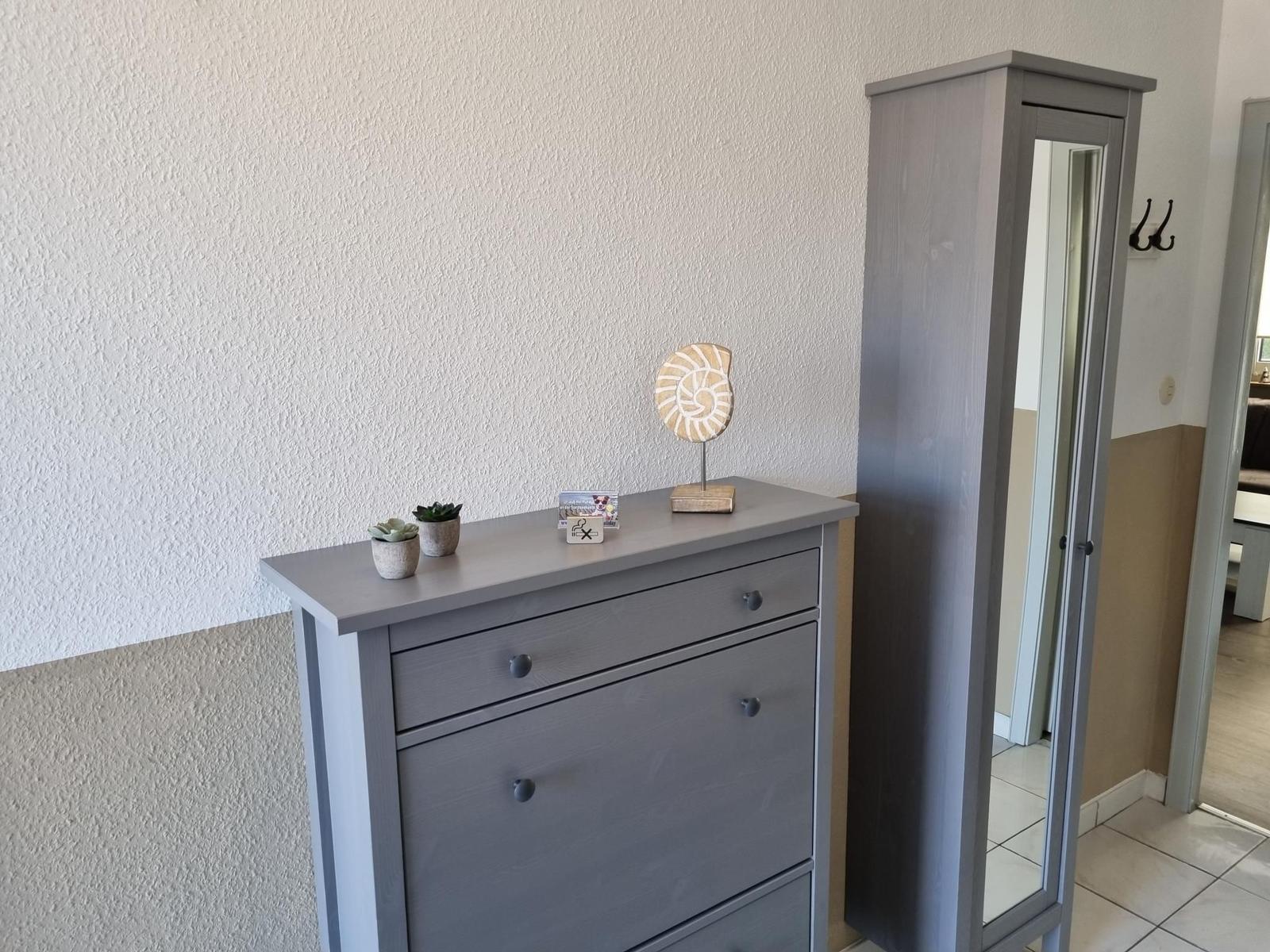 Schmucktisch mit Pflanzen und Dekorationsgegenständen neben einem Spiegelschrank.