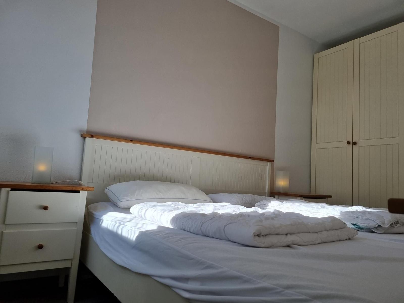 Schlafzimmer mit Bett, Nachttisch und Kleiderschrank.