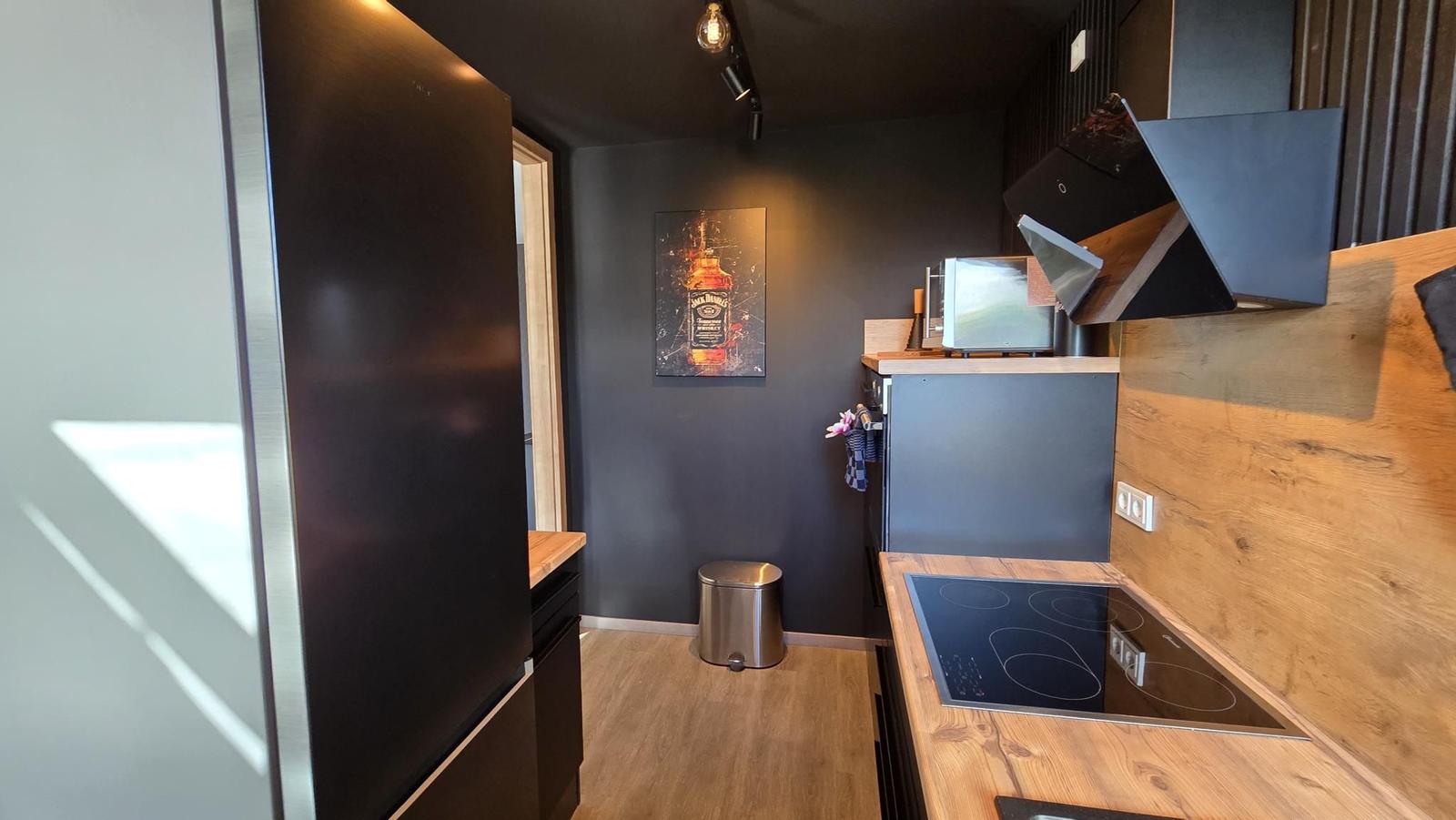 Küche mit Holzoberflächen, Induktionskochfeld und Kühlschrank.