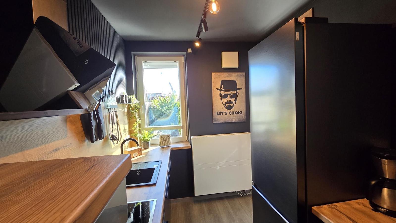 Küche mit Holzoberfläche, Kühlschrank und Fenster mit Blick auf Garten.