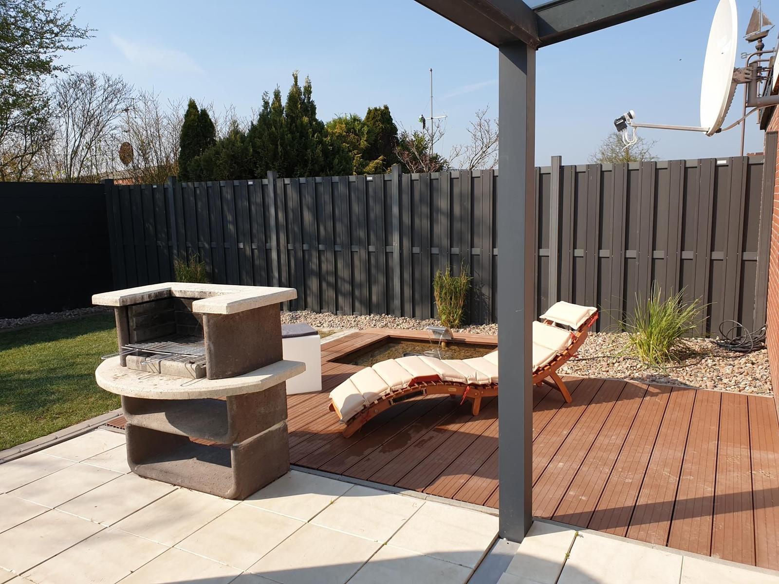 Terrasse mit Grill, Liegestühlen und Pool unter Pavillon.