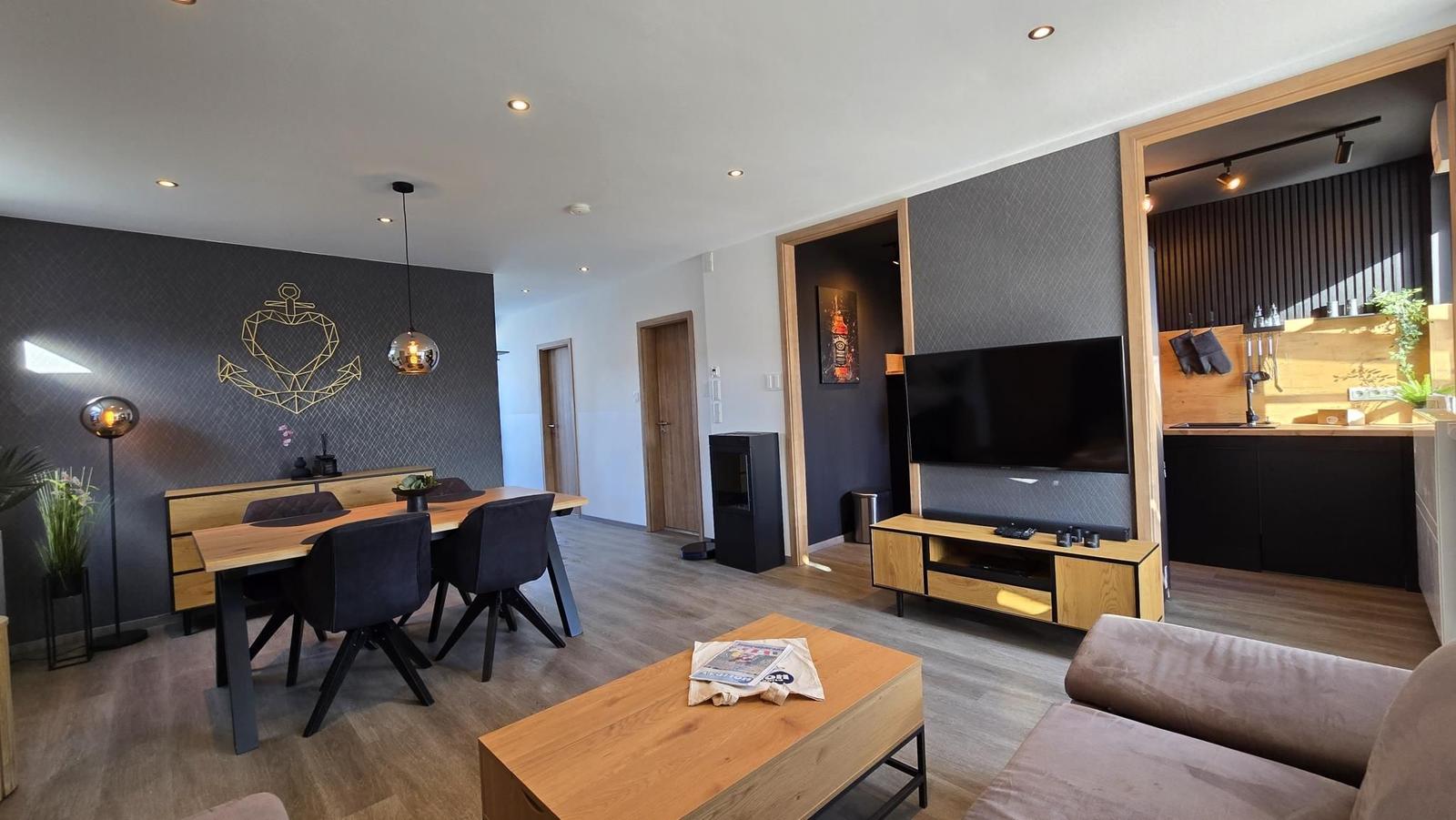 Wohnzimmer mit Essbereich, TV und Küche. Holzmöbel und moderne Beleuchtung.