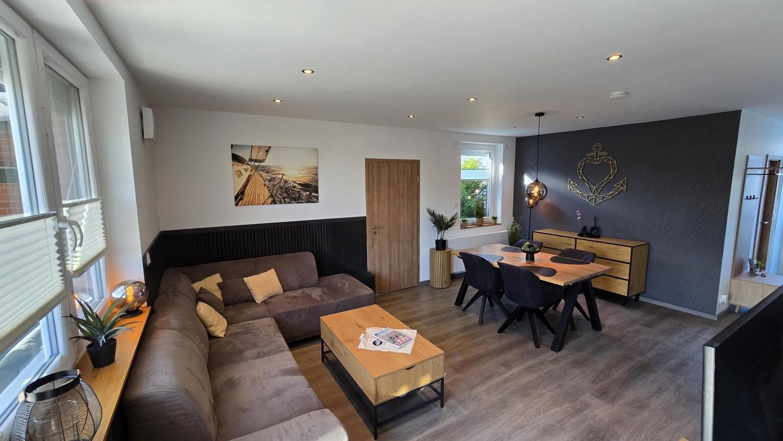 Wohn- und Essbereich mit Sofa, Esstisch und Wanddekoration.