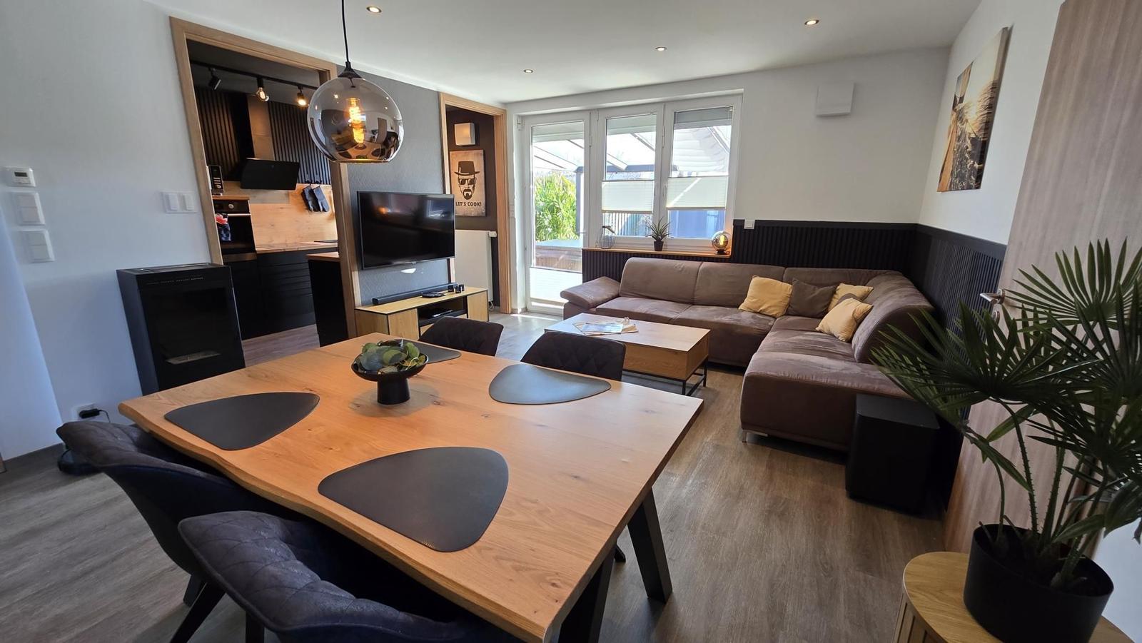 Wohnzimmer mit Essbereich, Sofa und Küchenbereich. Holztisch und -stühle.