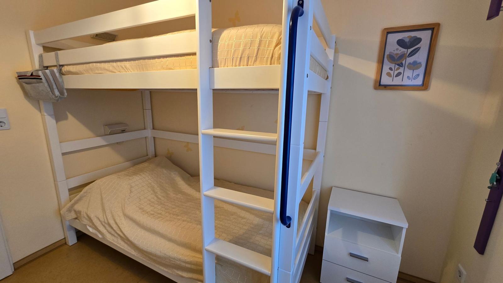 Zimmer mit Doppelstockbett, Nachttisch und Wandbild.