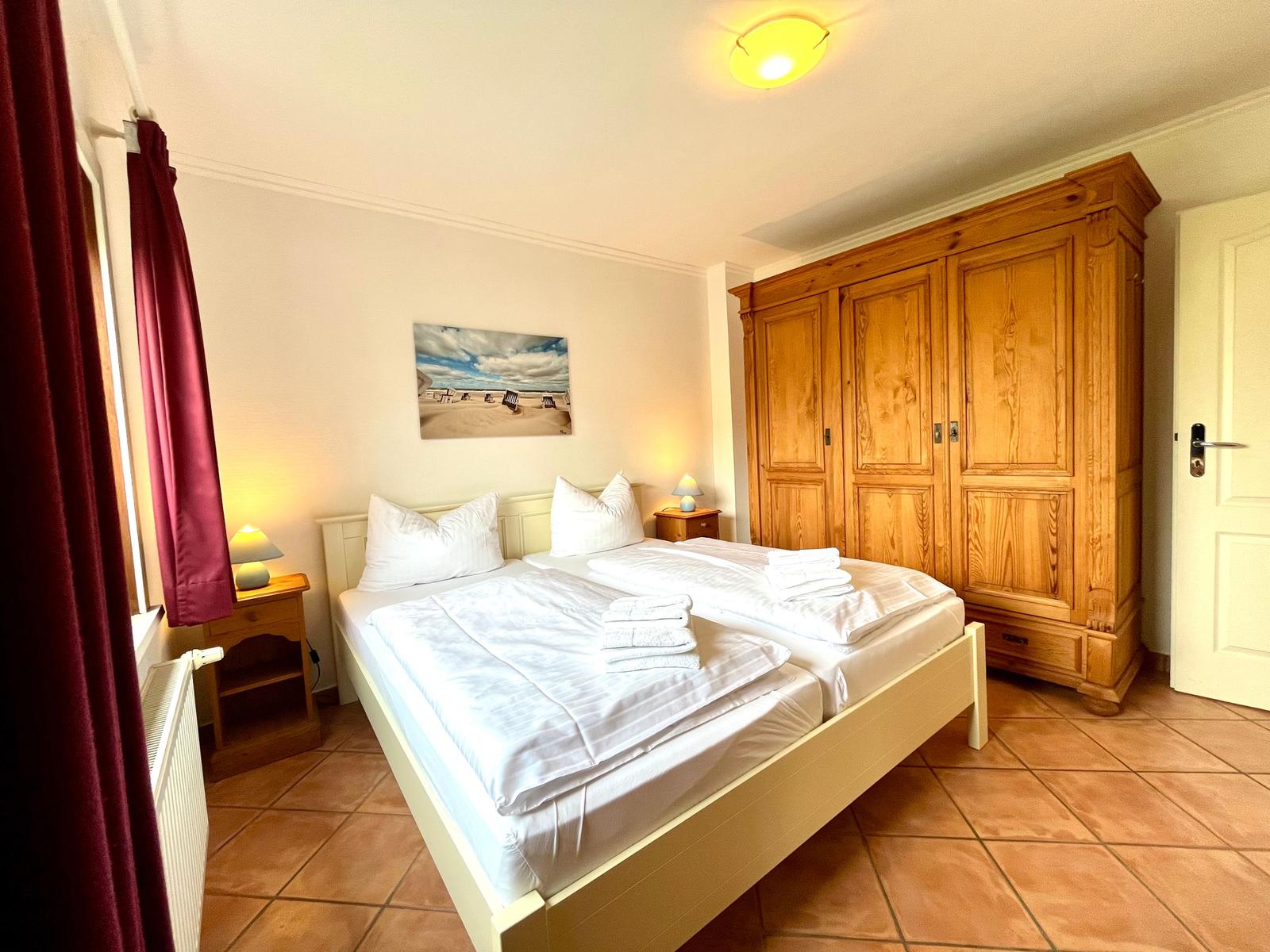 Schlafzimmer mit Doppelbett, Holzschrank und Nachttischen.