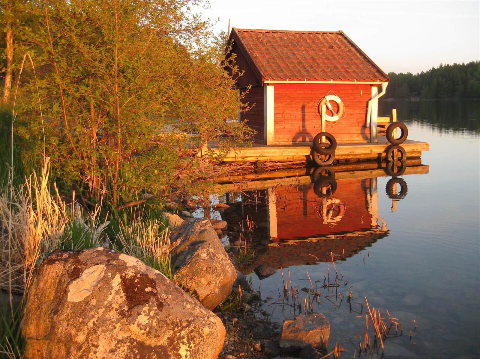 Rotes Bootshaus am See mit Steg und Rettungsring.
