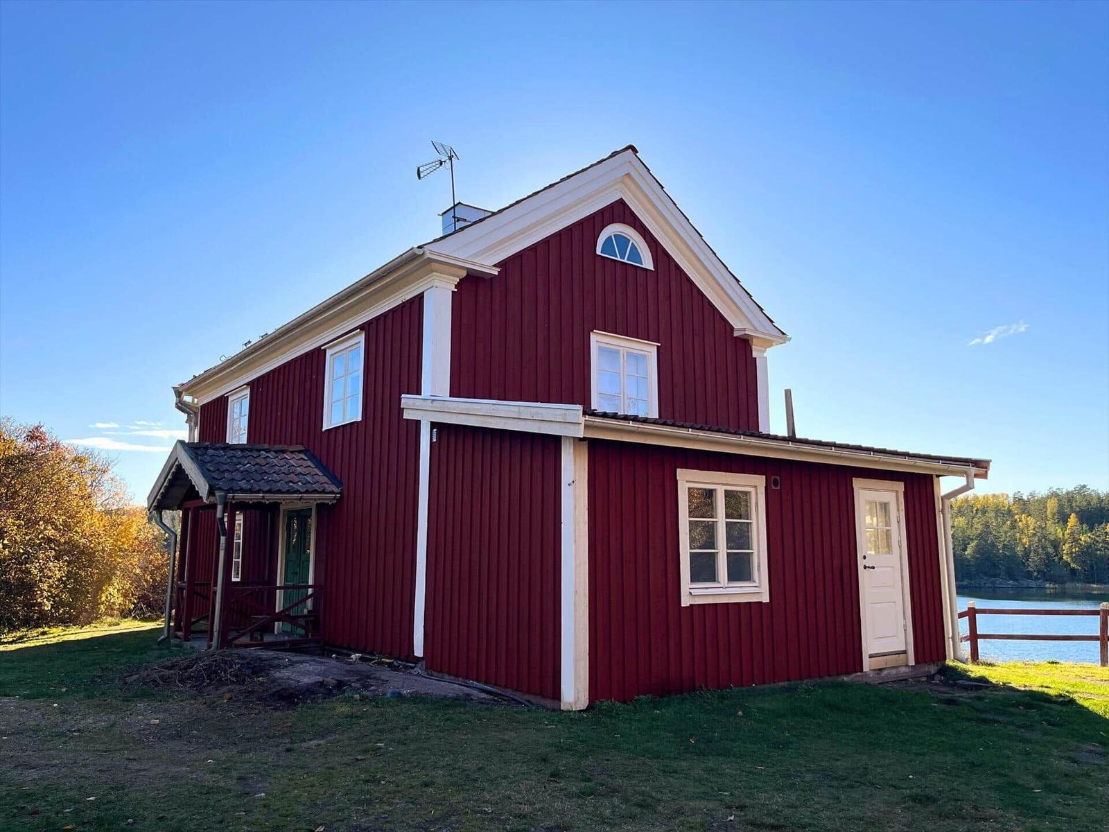 Rotes Holzhaus mit weißem Rahmen und Fenstern am See