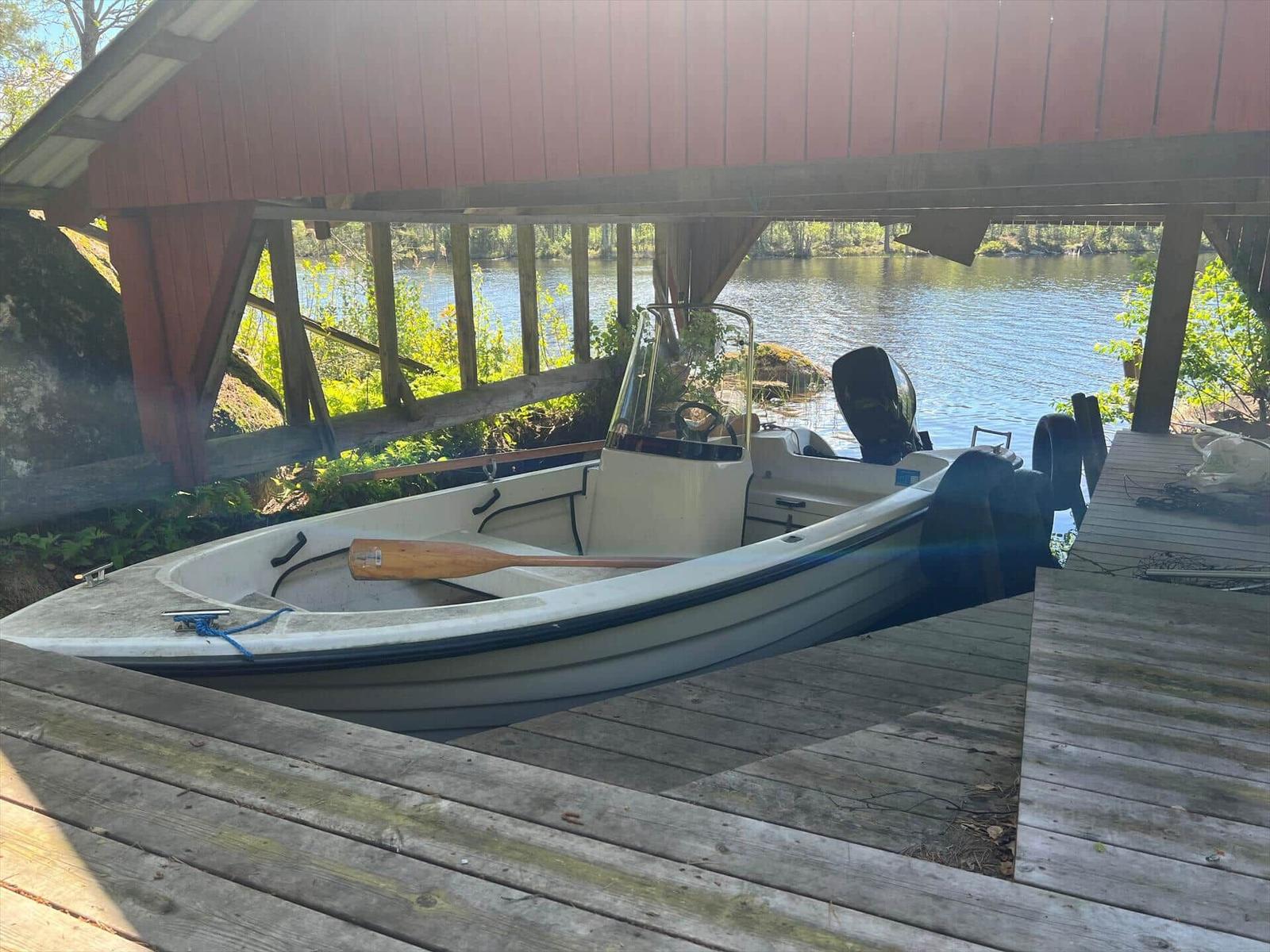 Ein Motorboot steht auf einem Holzsteg unter einem roten Dach.