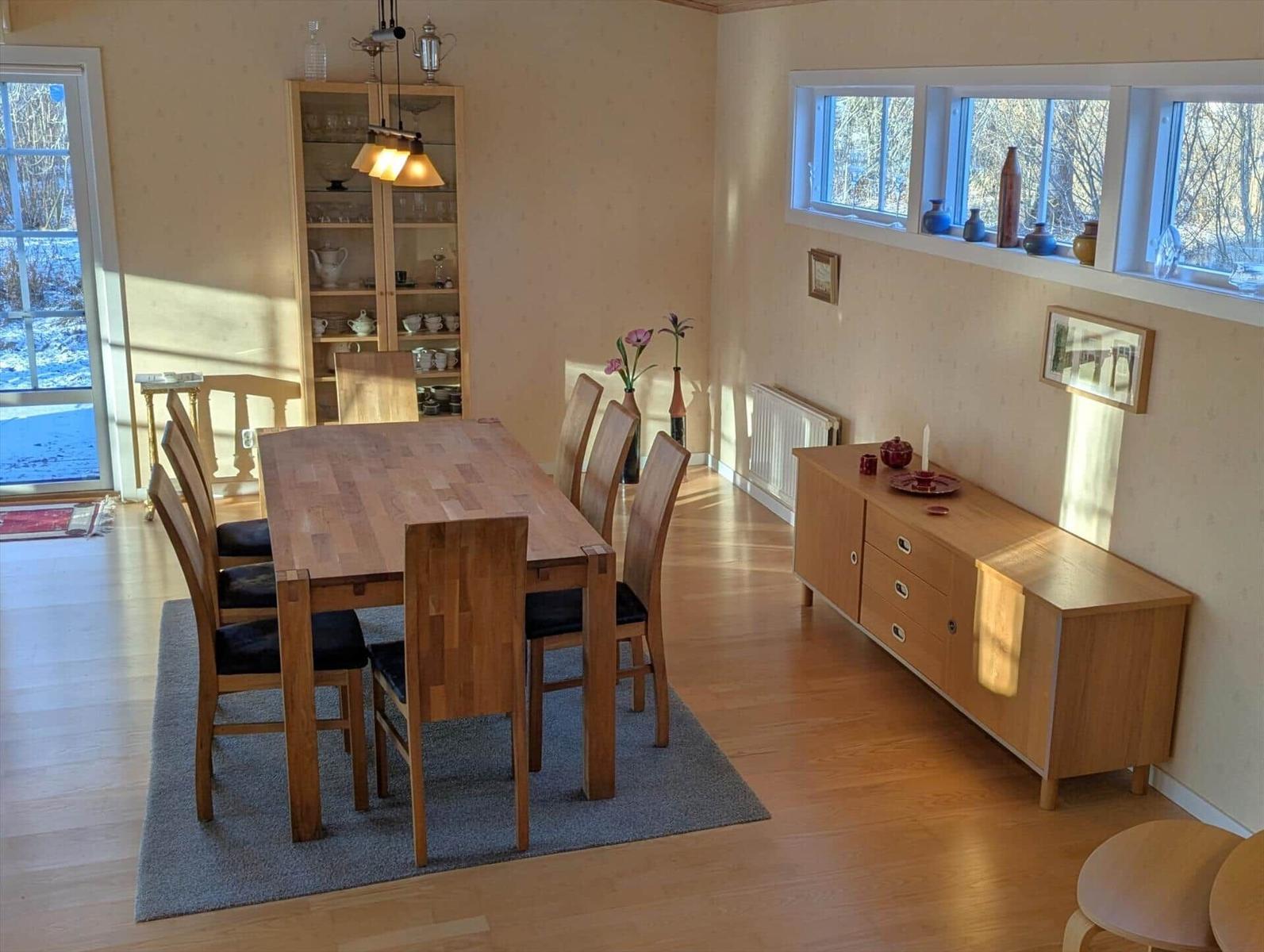 Esszimmer mit Holztisch, Stühlen und Sideboard. Fenster mit Blick auf Schnee.