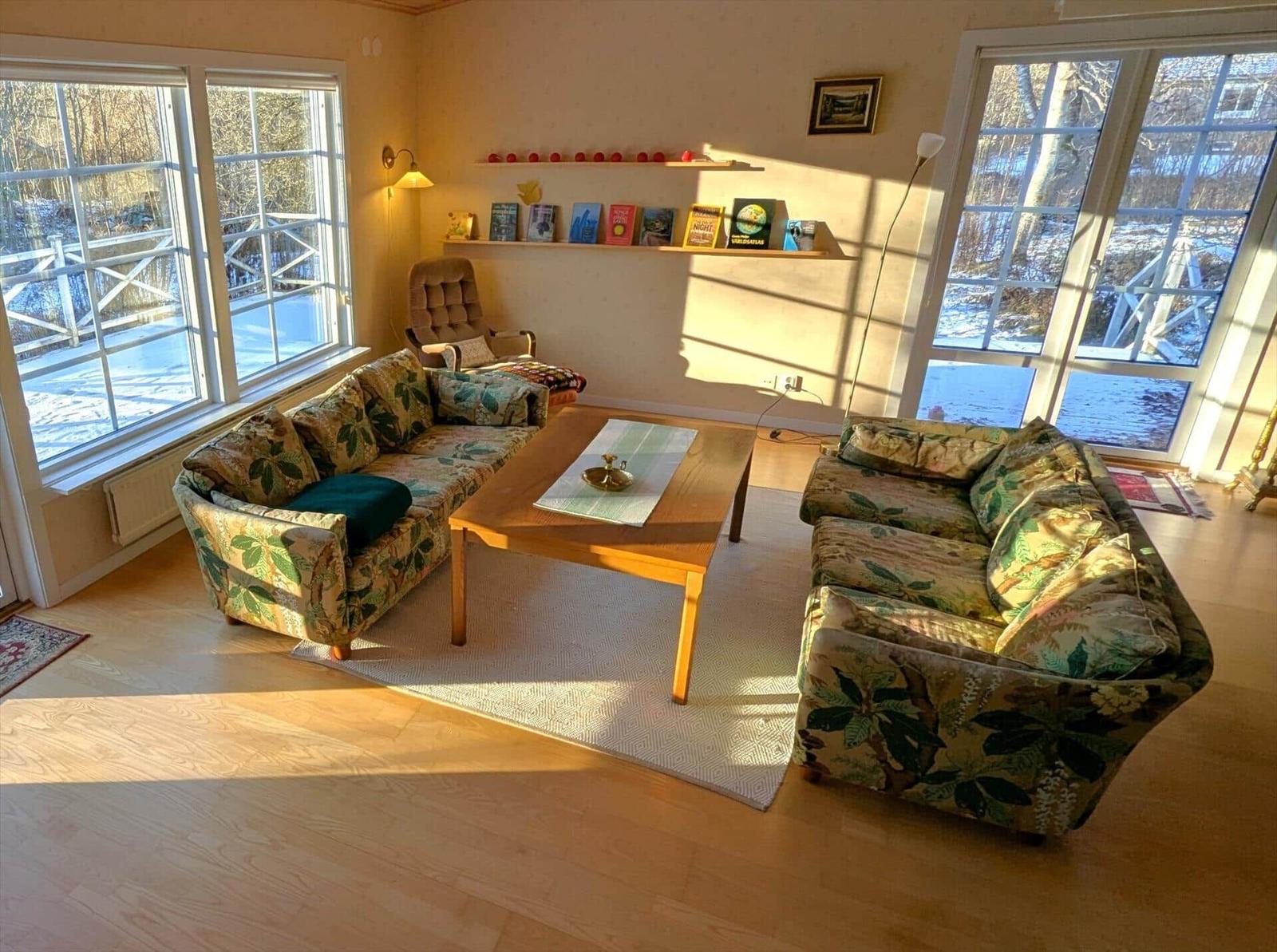 Wohnzimmer mit zwei Sofas, Tisch und Fenstern zum Ausblick.