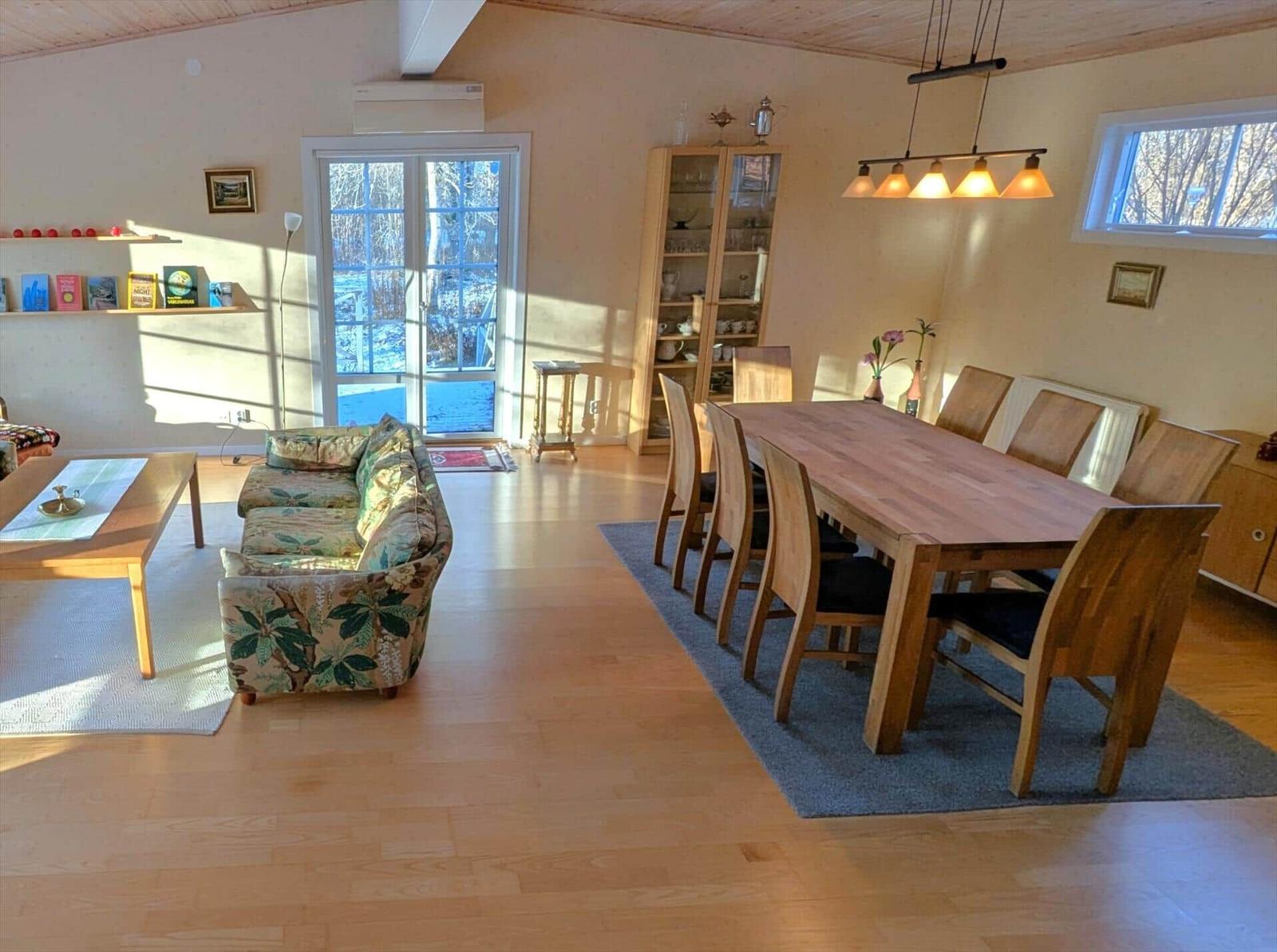 Wohn- und Essbereich mit Holzboden, Sofa, Esstisch und Fenster.