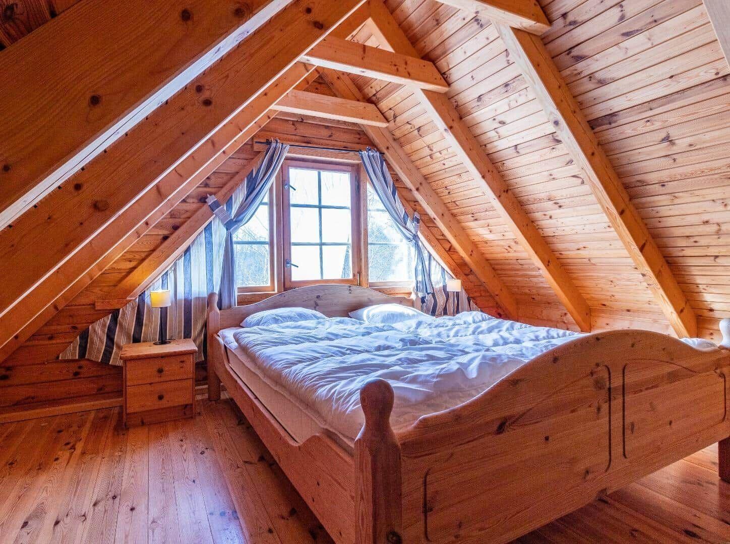 Schlafzimmer mit Holzbett, Fenster und Holzwandverkleidung