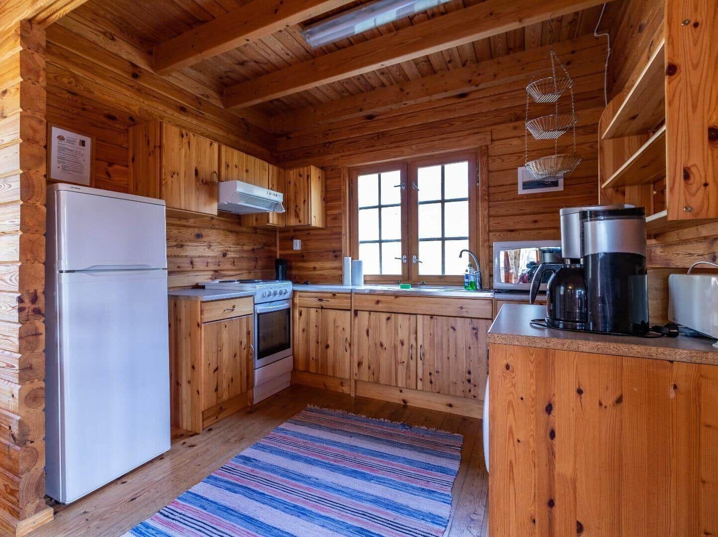 Küche mit Holzelementen, Kühlschrank, Herd und Fenster.