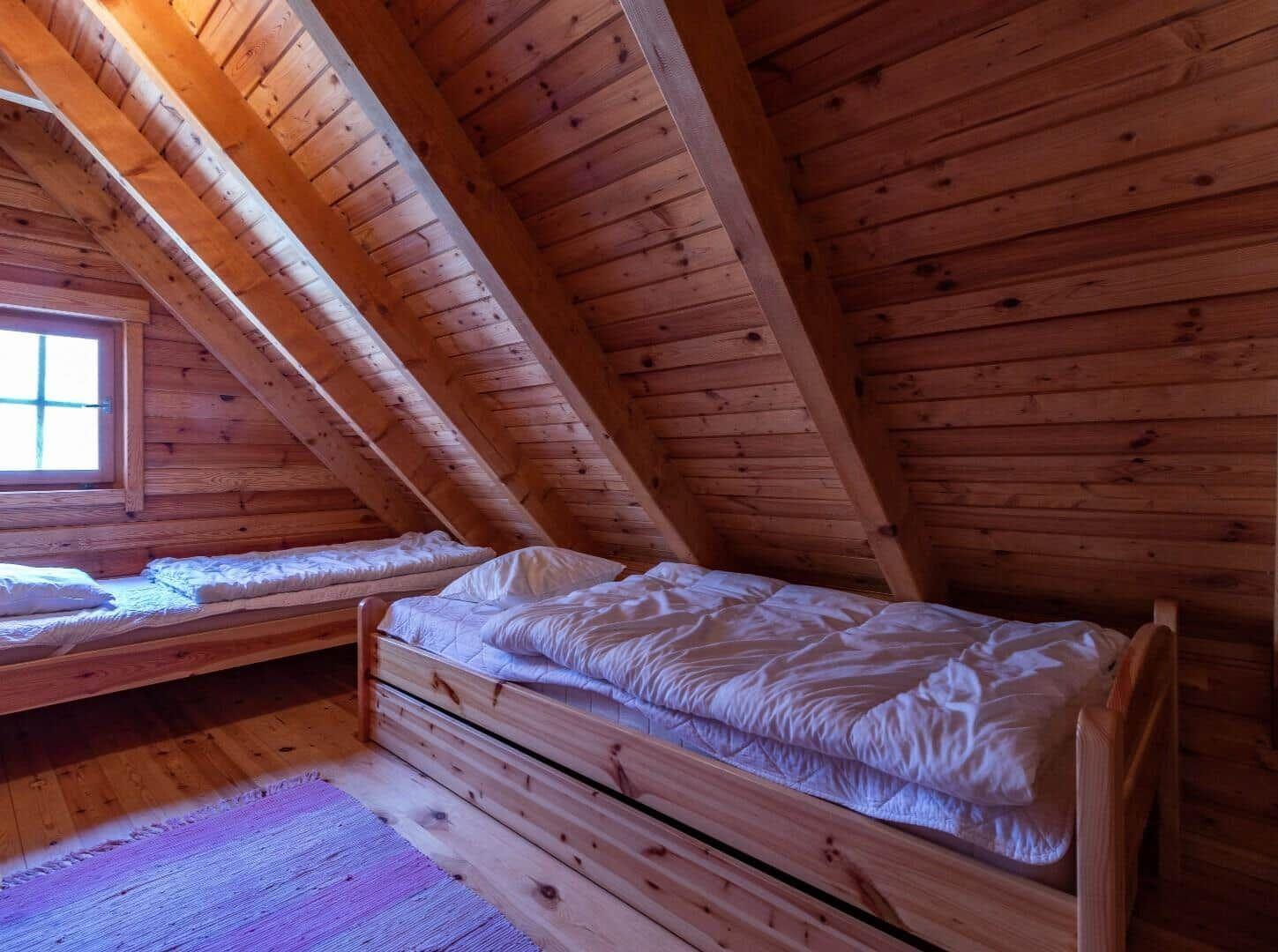 Zwei Betten in einem Holzhaus mit Dachschrägen und Fenster