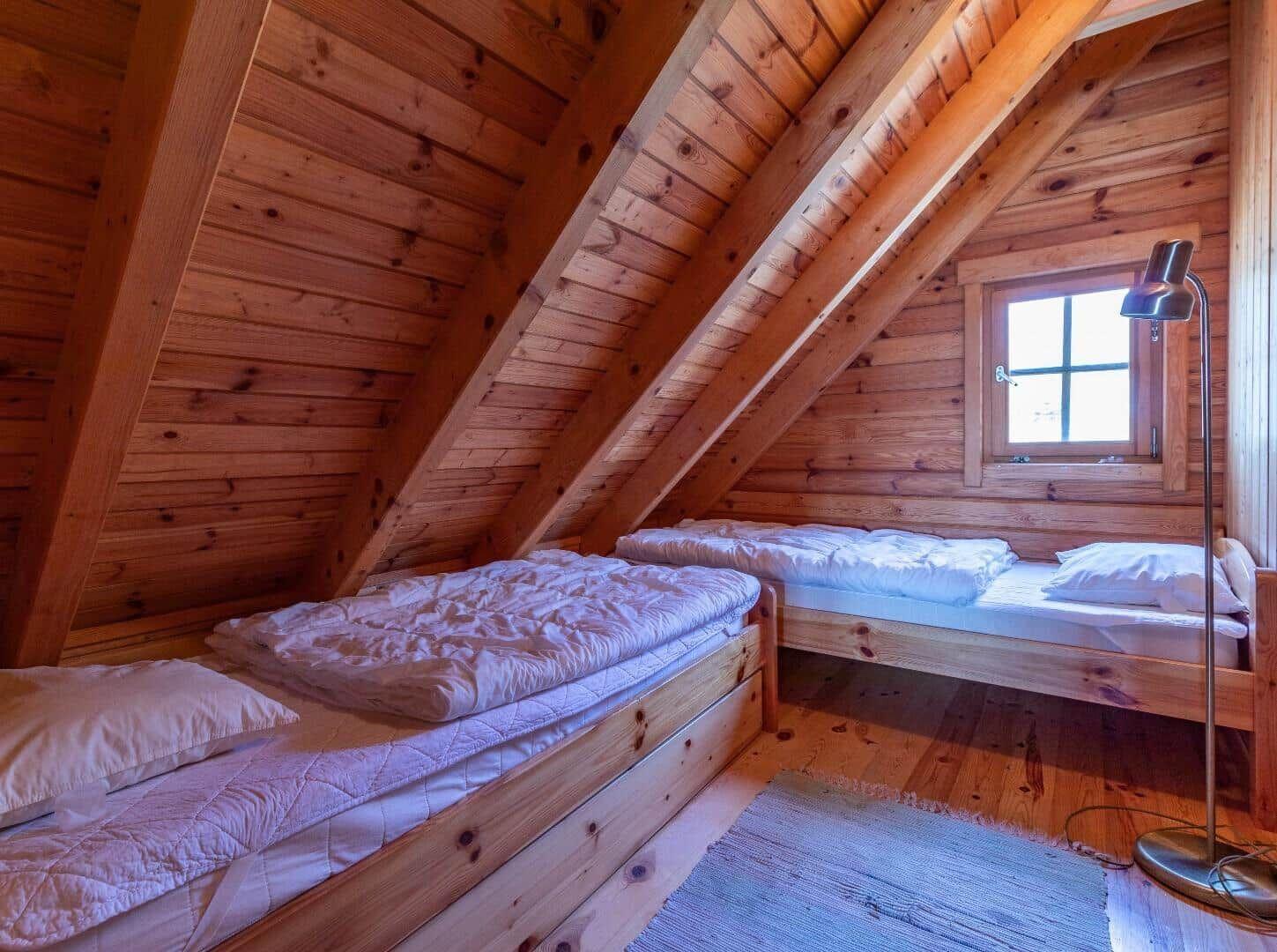 Zimmer mit zwei Betten, Holzwand und Dachfenster.