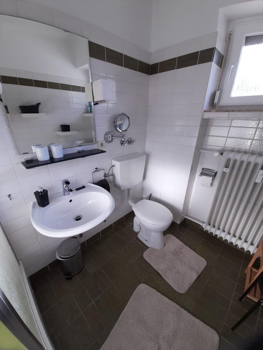 Badezimmer mit Waschbecken, Toilette und Fenster.