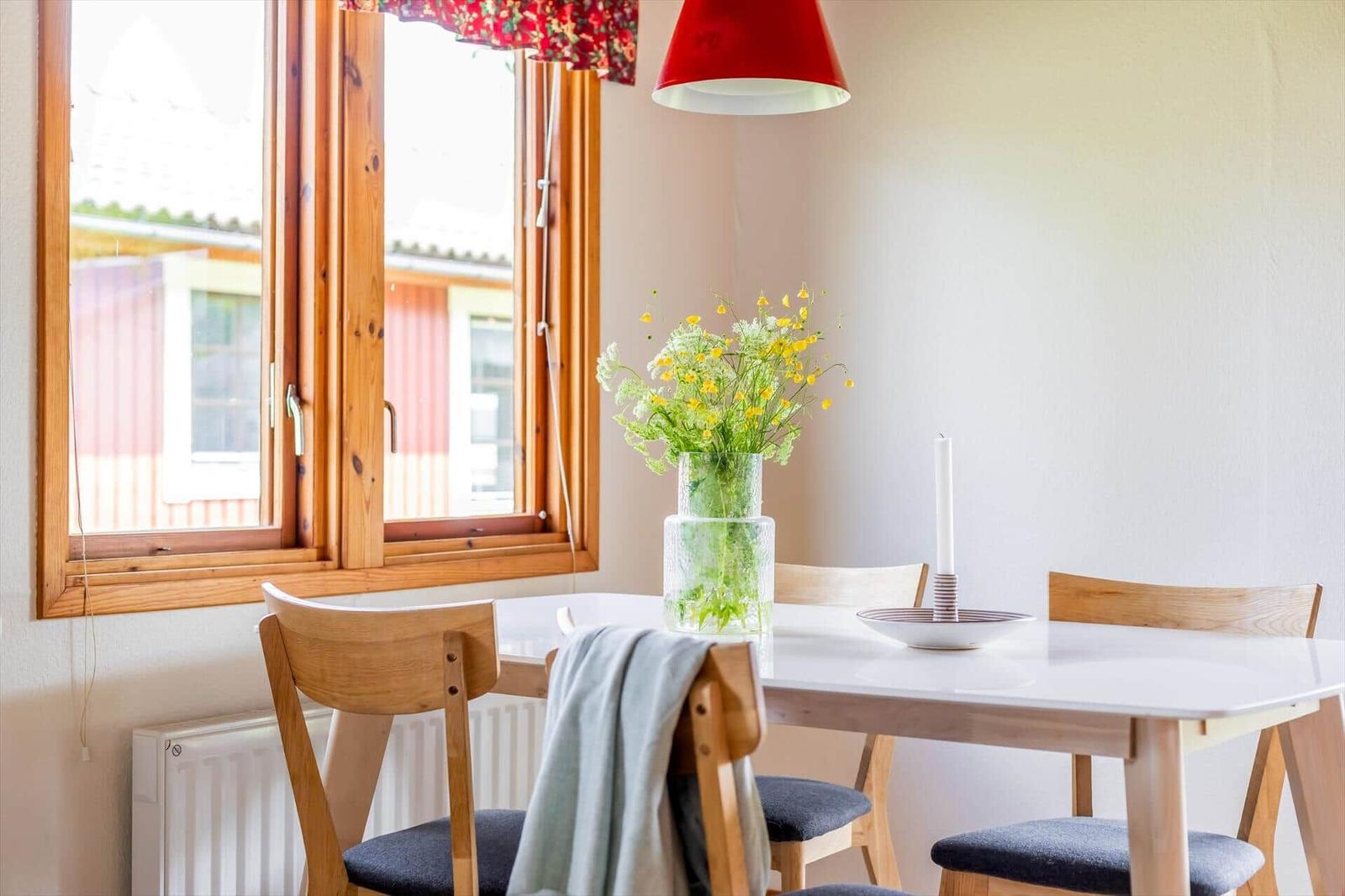 Esstisch mit Stühlen, Blumen und Laterne neben Fenster.