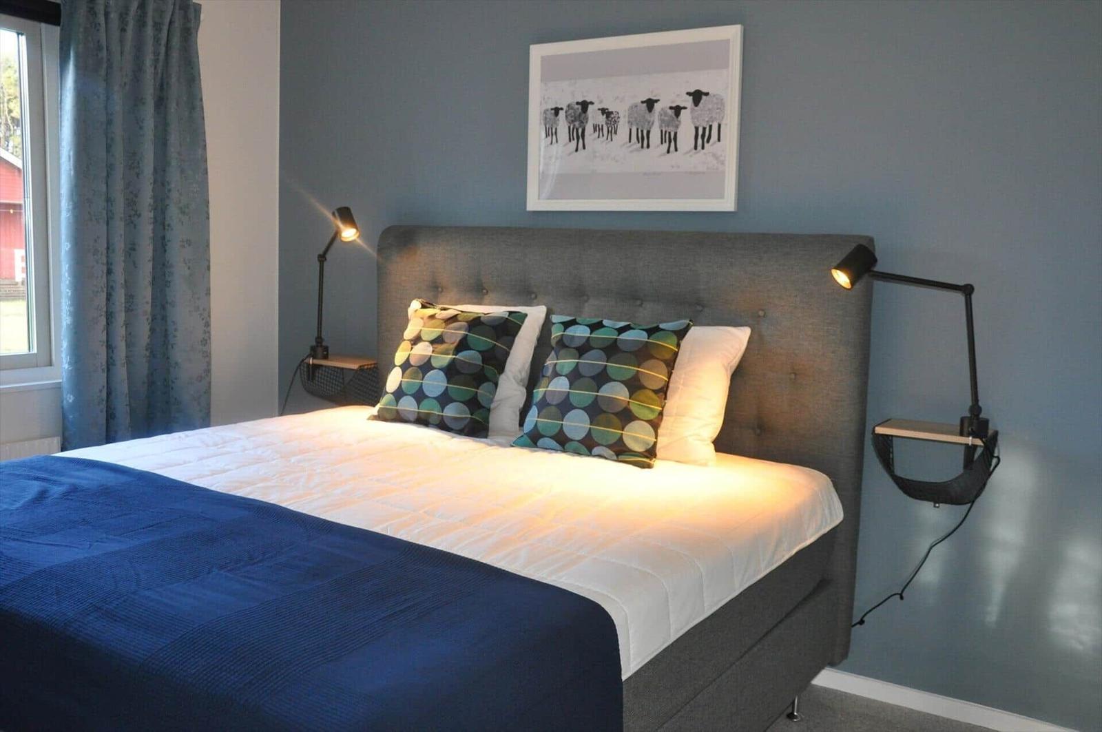 Schlafzimmer mit Bett, Wandlampen und Bild an der Wand.