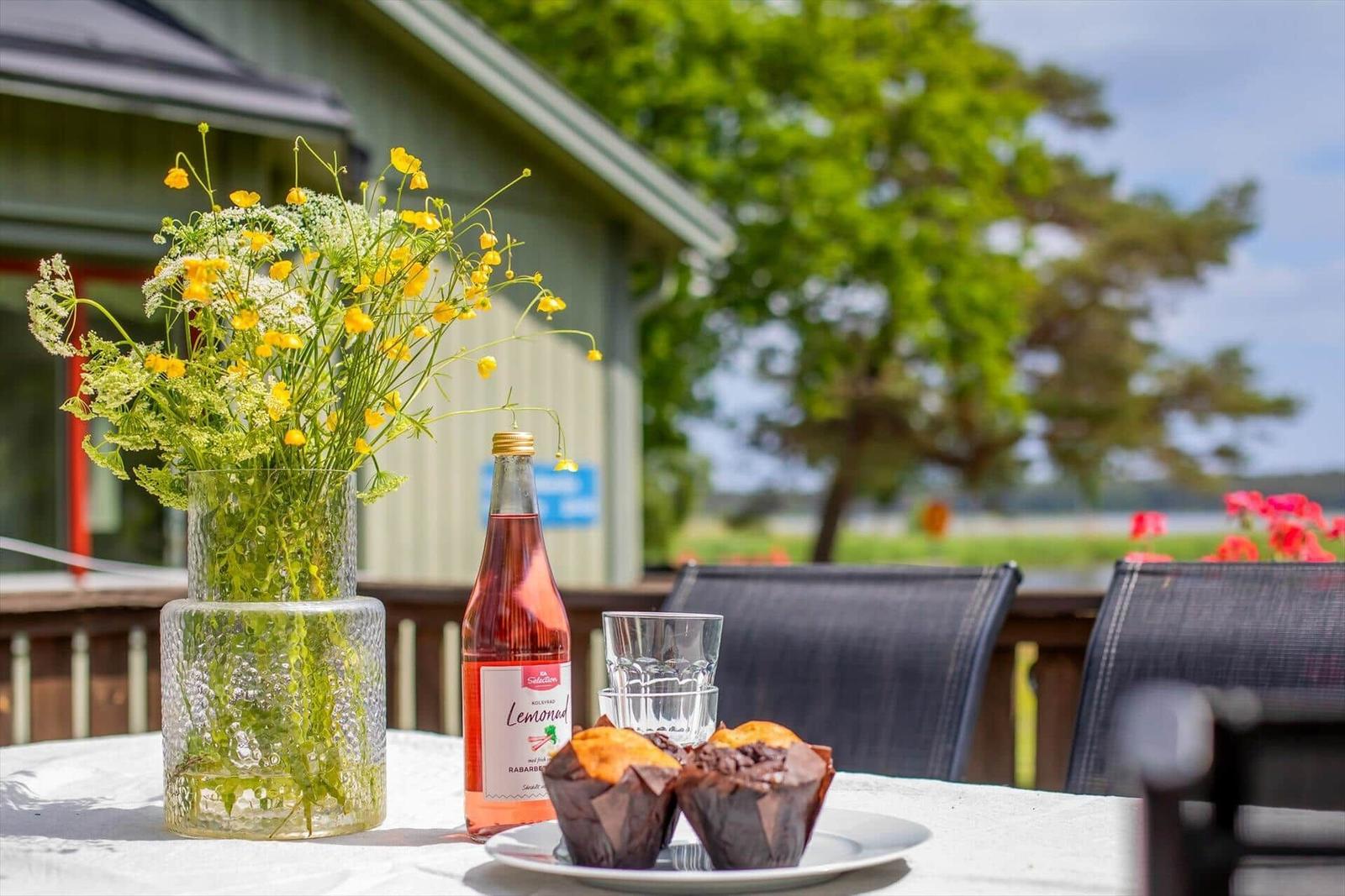 Tisch mit Blumen, Muffins und Getränk auf Terrasse