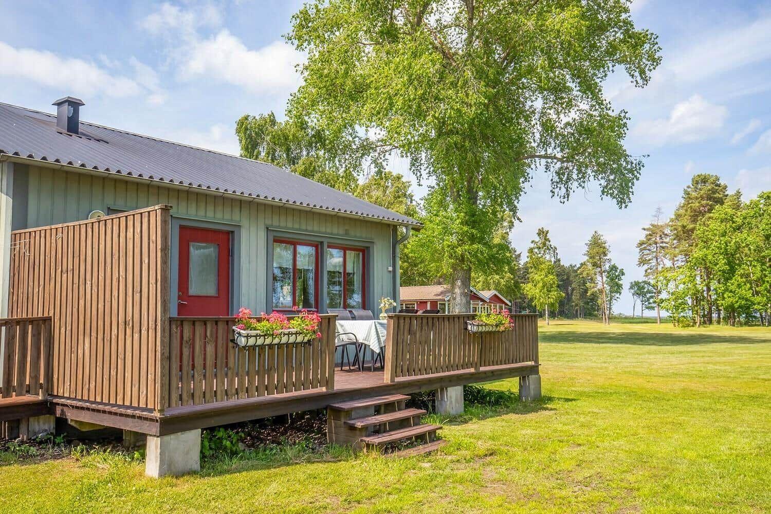 Haus mit Holzveranda, Garten und großen Fenstern.
