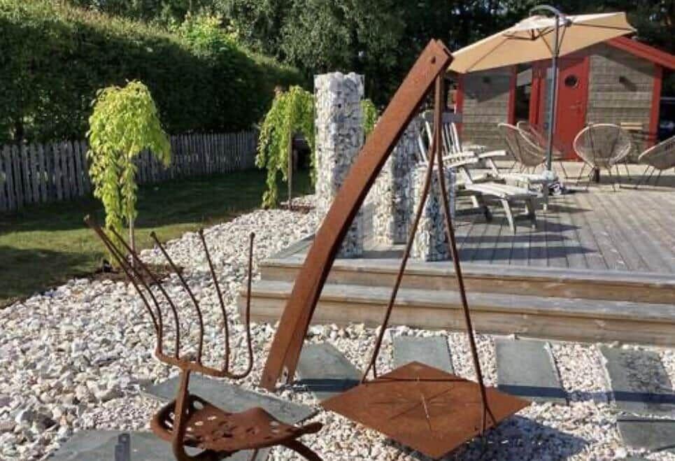 Hinterhof mit Holzterrasse, Sonnenschirm und rustikalem Gartenmöbel.