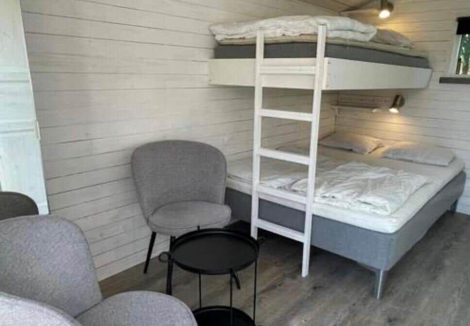 Zimmer mit Doppelstockbett, Stuhl und kleinem Tisch.