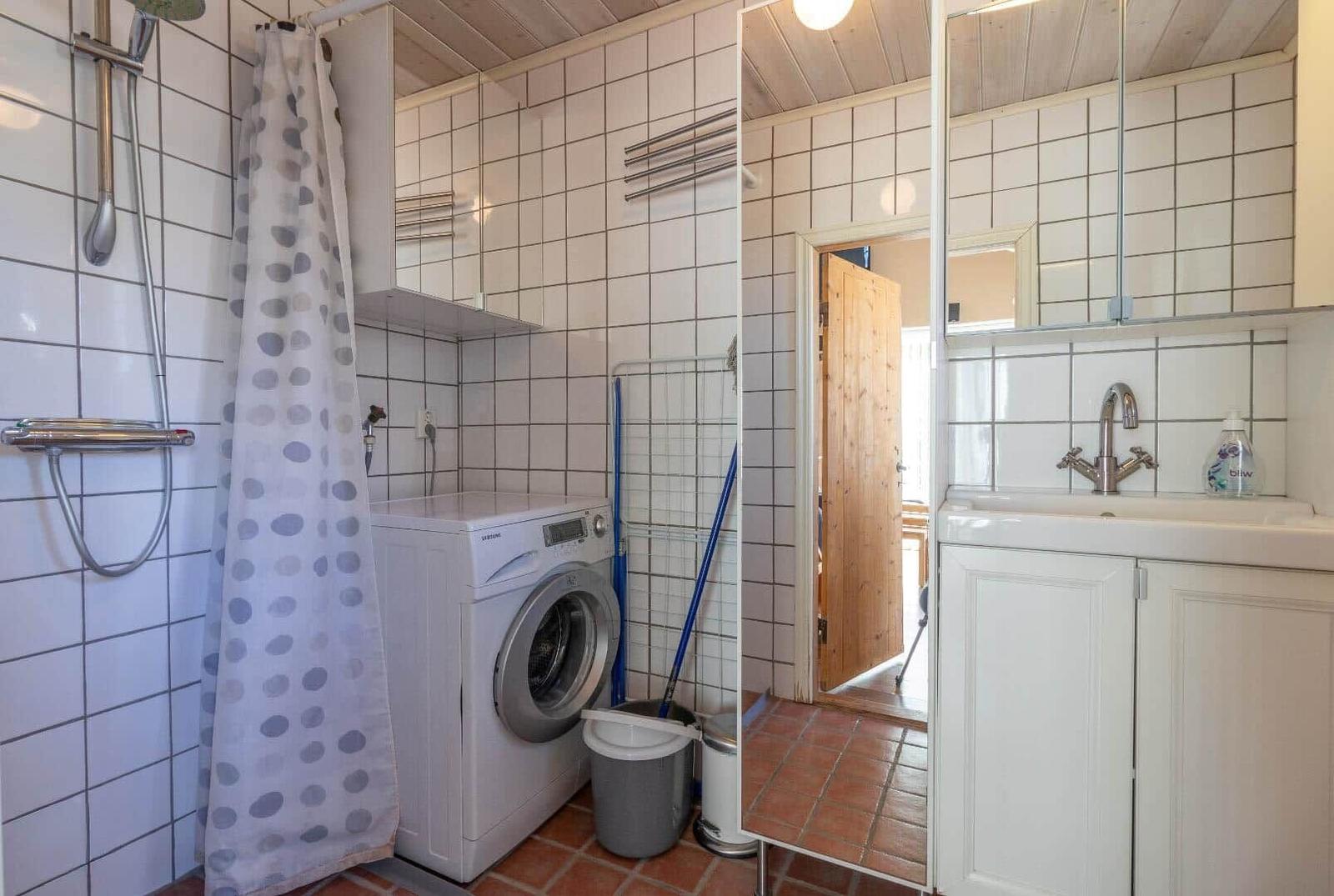 Badezimmer mit Dusche, Waschmaschine und Waschbecken