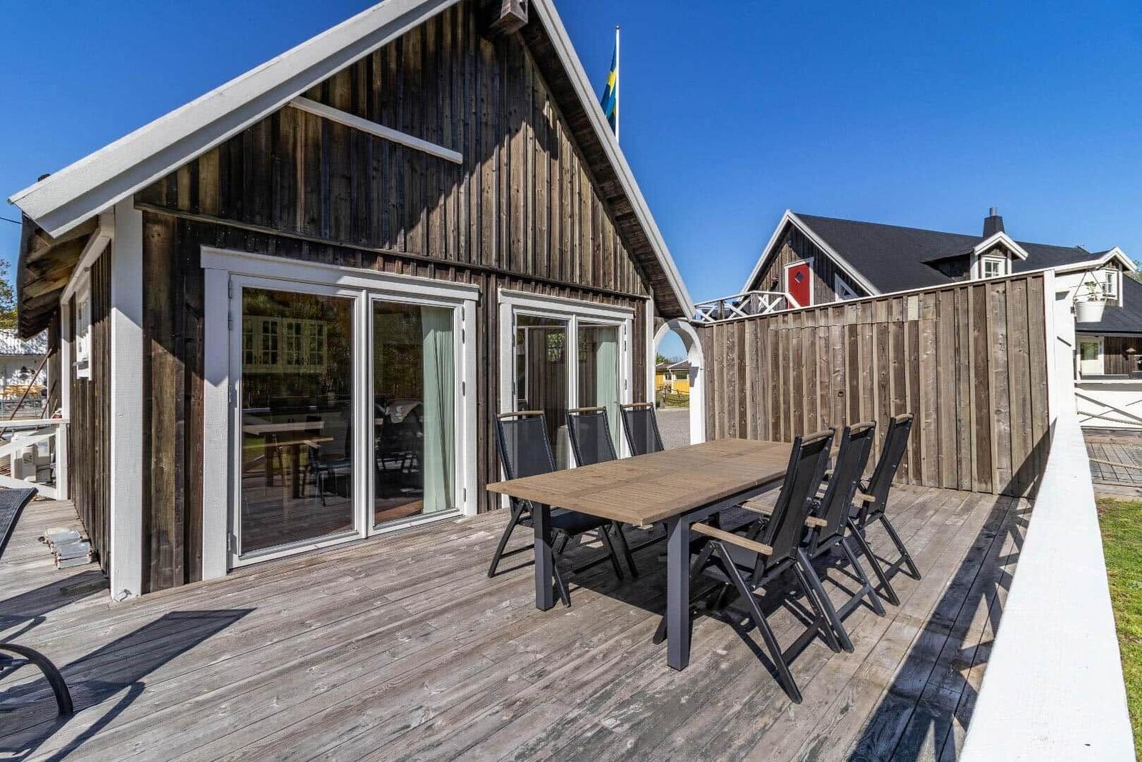 Terrasse mit Tisch und Stühlen vor einem Holzhaus mit Schiebetüren.