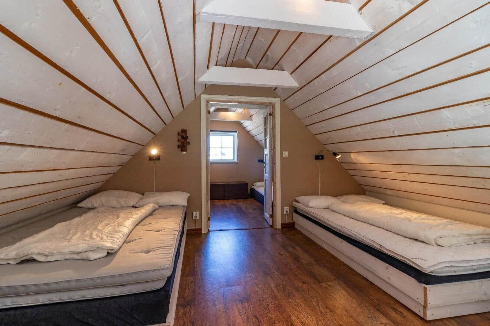 Zwei Betten in einem Dachzimmer mit Holzdecke und -boden.