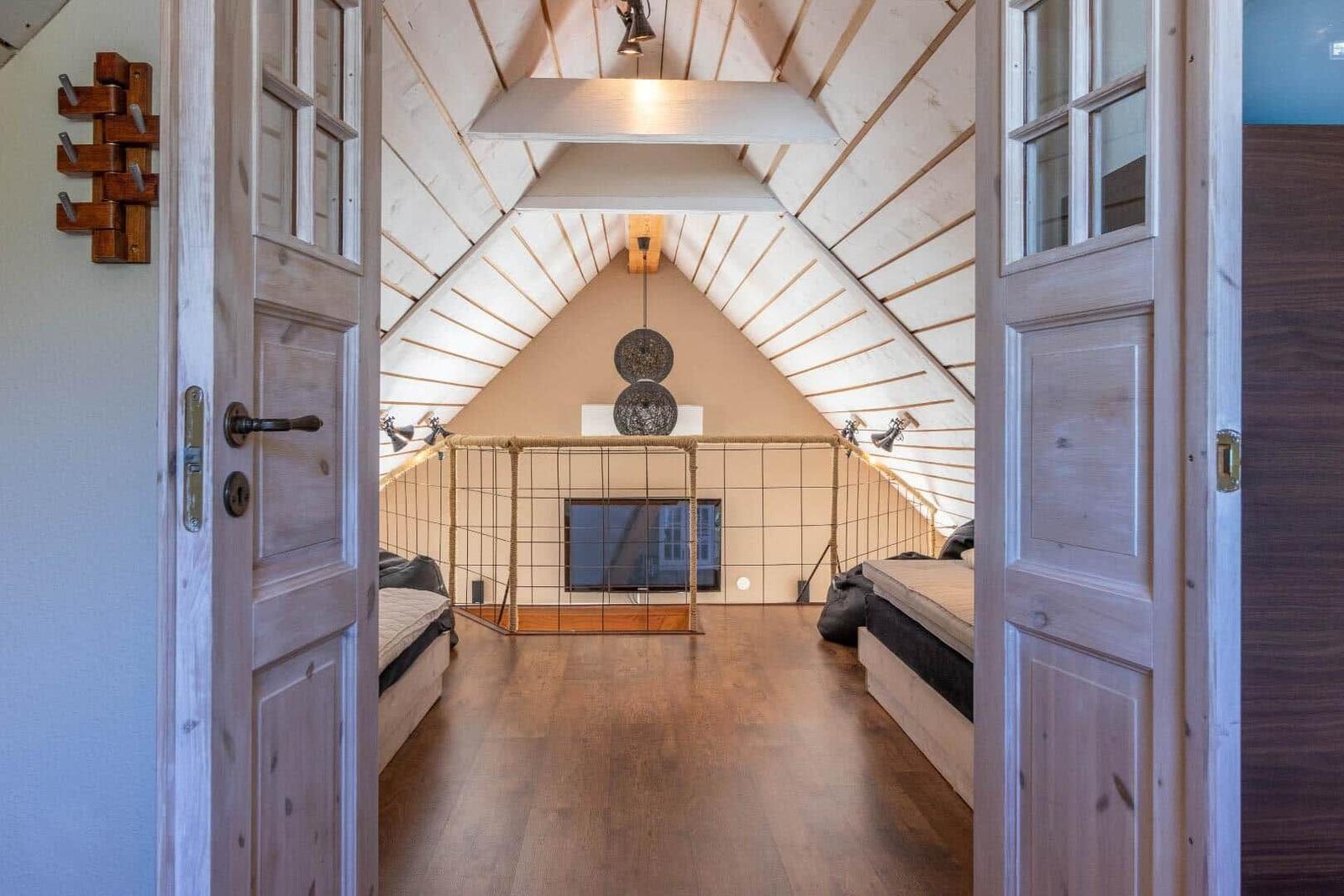 Dachgeschosszimmer mit Holzboden, Bett und Fernseher