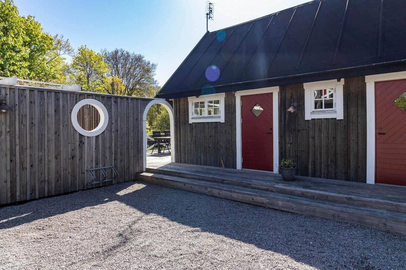 Haus mit roter Tür, Holzwand und Terrasse im Freien.