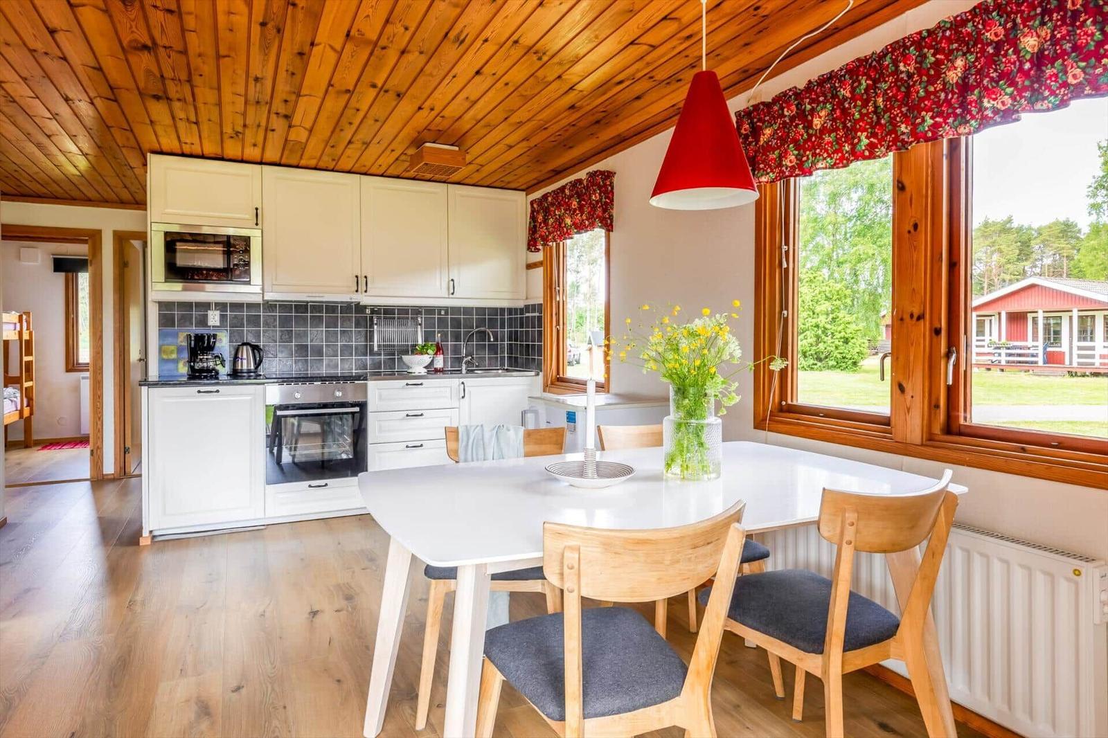 Küche mit Esstisch, Fensterblick auf Garten und rotes Haus.